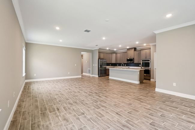 Spacious living area with tiled flooring and modern kitchen appliances in the background.