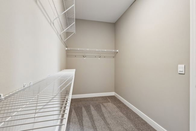 Empty closet with wire shelving and gray carpeted floor.