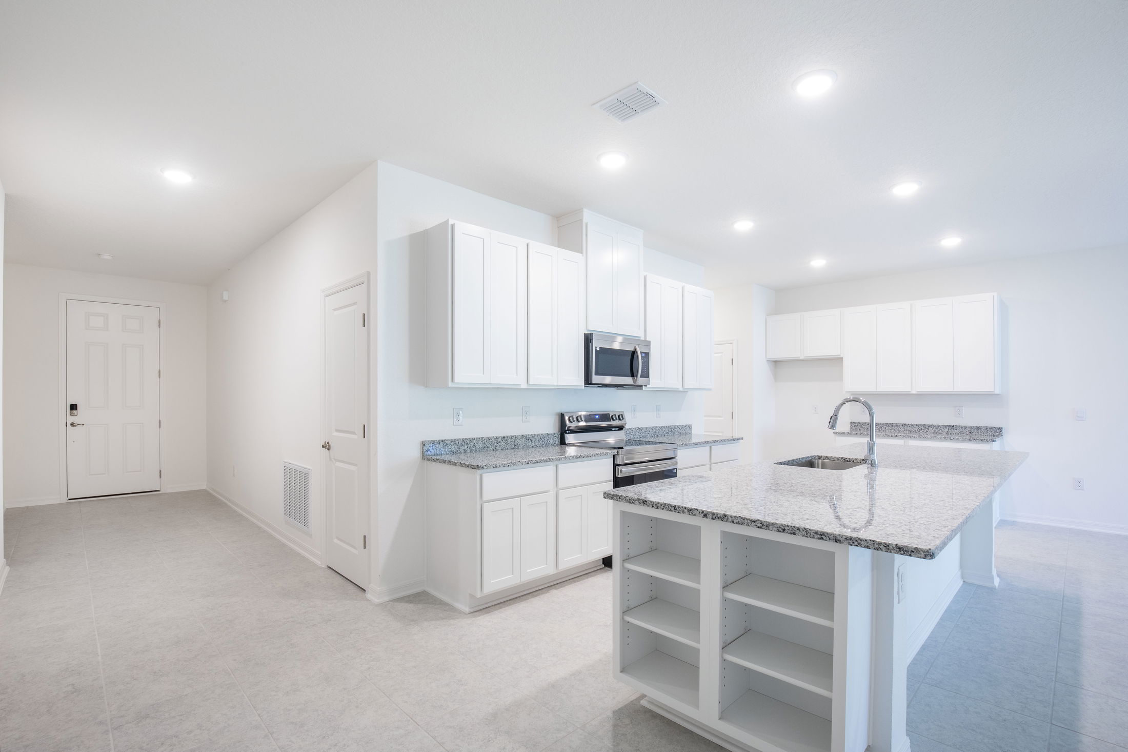 Modern kitchen interior with white cabinets, granite countertops, and stainless steel appliances.