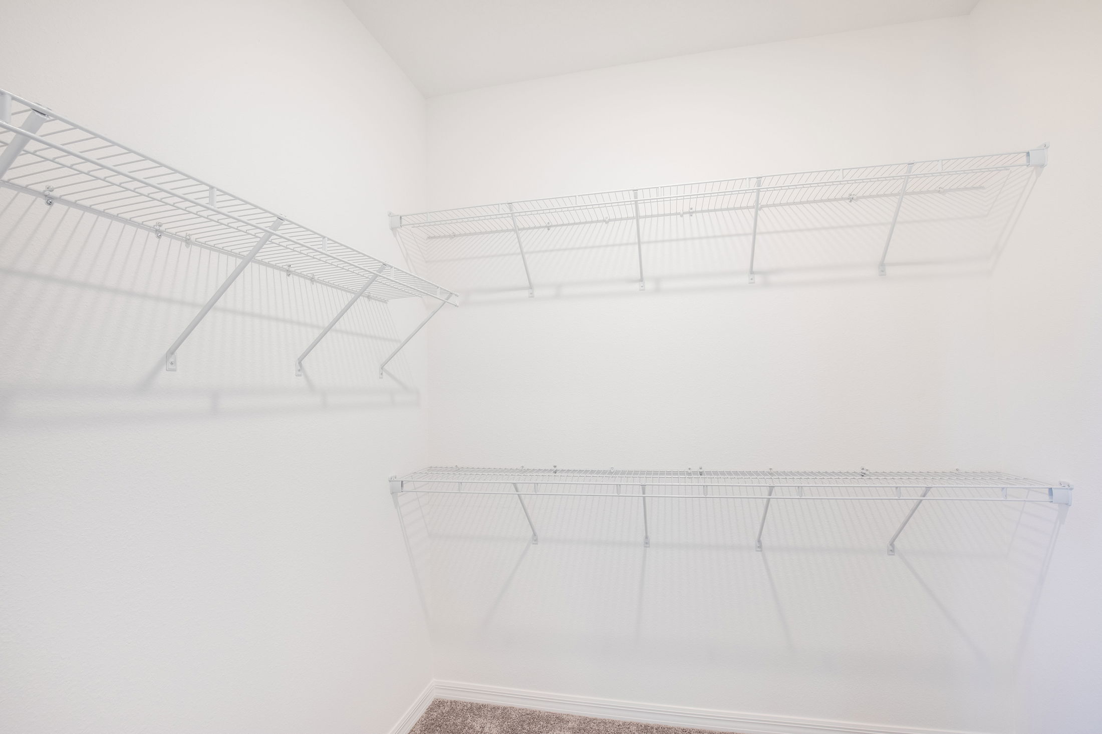 Empty white closet with multiple metal wire shelves installed on the walls.