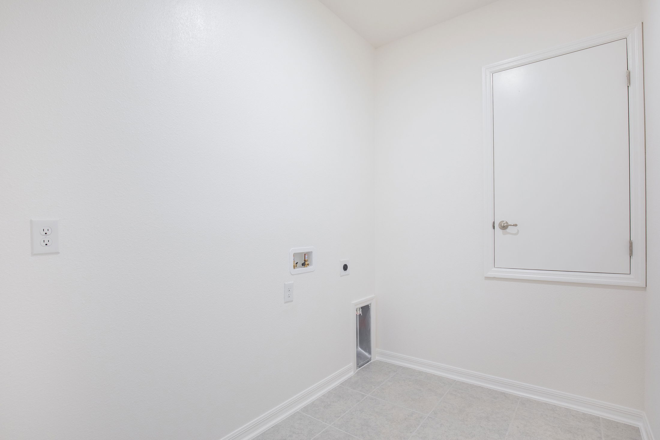 Empty white laundry room with utility connections and a small access panel.