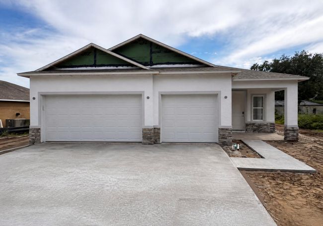 Newly constructed single-family home with two garages and exposed foundation.