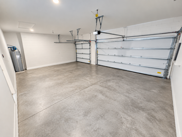 Spacious empty garage with two closed overhead doors and concrete flooring.
