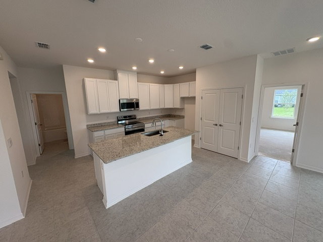 Modern kitchen with white cabinets, granite countertops, stainless steel appliances, and a dining area.