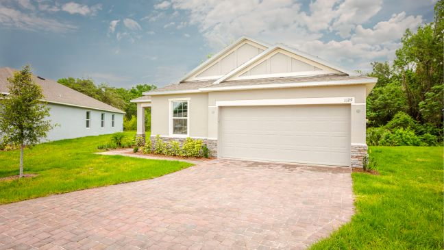 A modern single-family house with a gray garage door, stone accents, and a landscaped front yard.