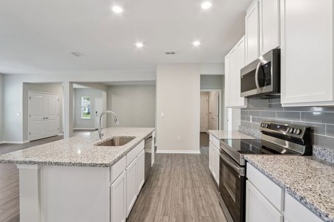 Modern kitchen featuring white cabinetry, granite countertops, and stainless steel appliances.