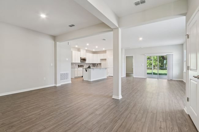 Spacious, modern living area with hardwood flooring and open kitchen design.