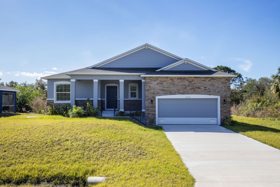 Single-story contemporary house with brick and siding exterior, two-car garage, and manicured lawn under a clear blue sky.