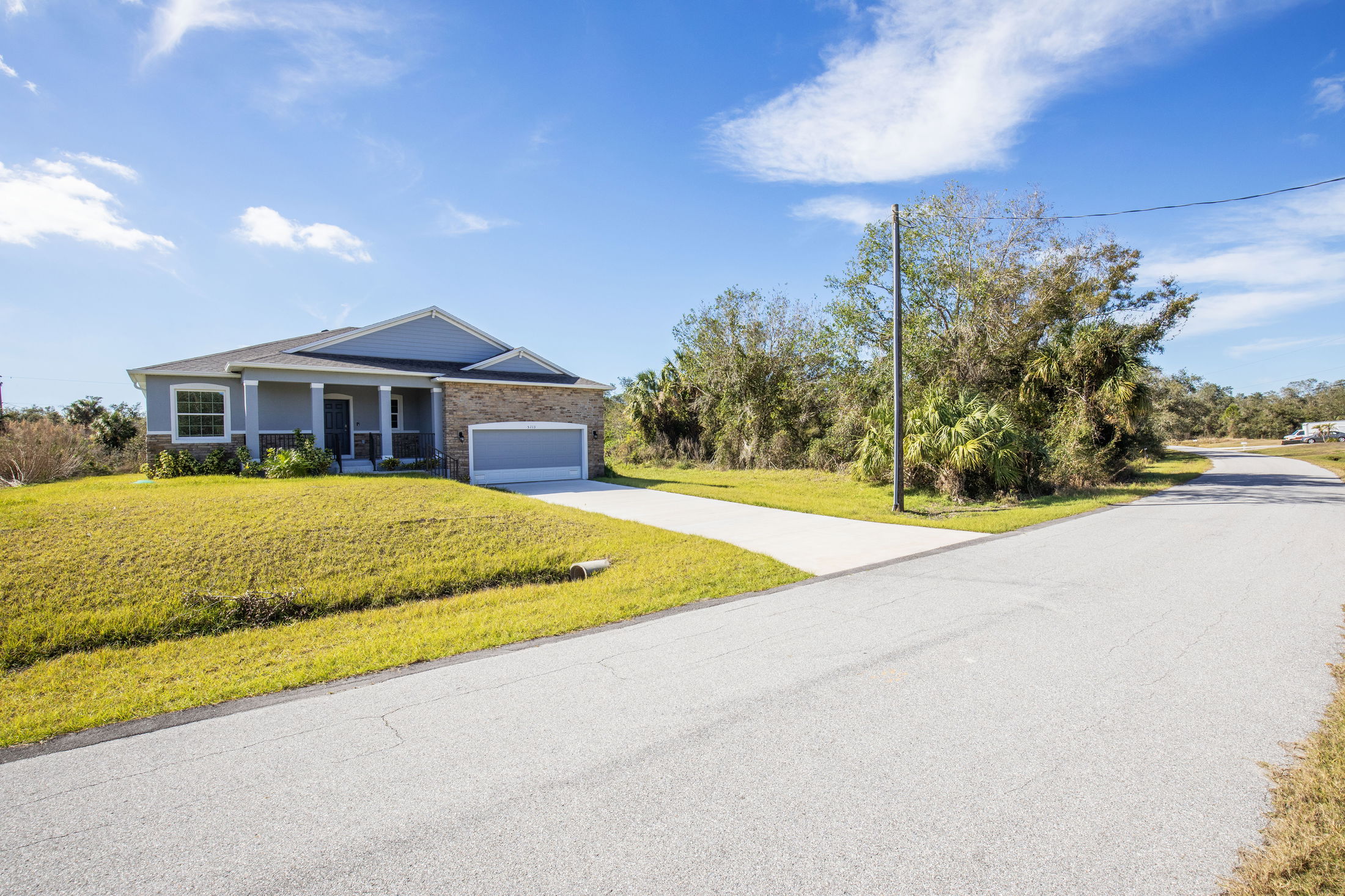 Single-story modern house with a two-car garage and a well-maintained lawn on a sunny day.