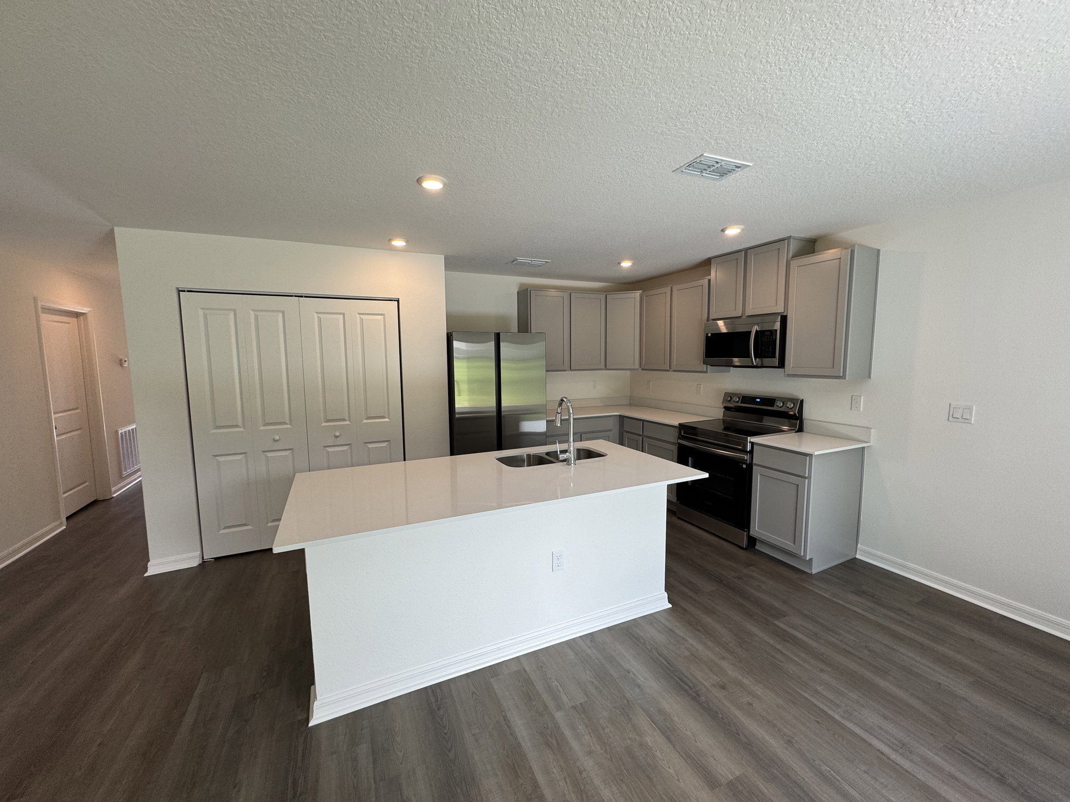 Modern kitchen featuring stainless steel appliances, a white island with a sink, and gray cabinetry.