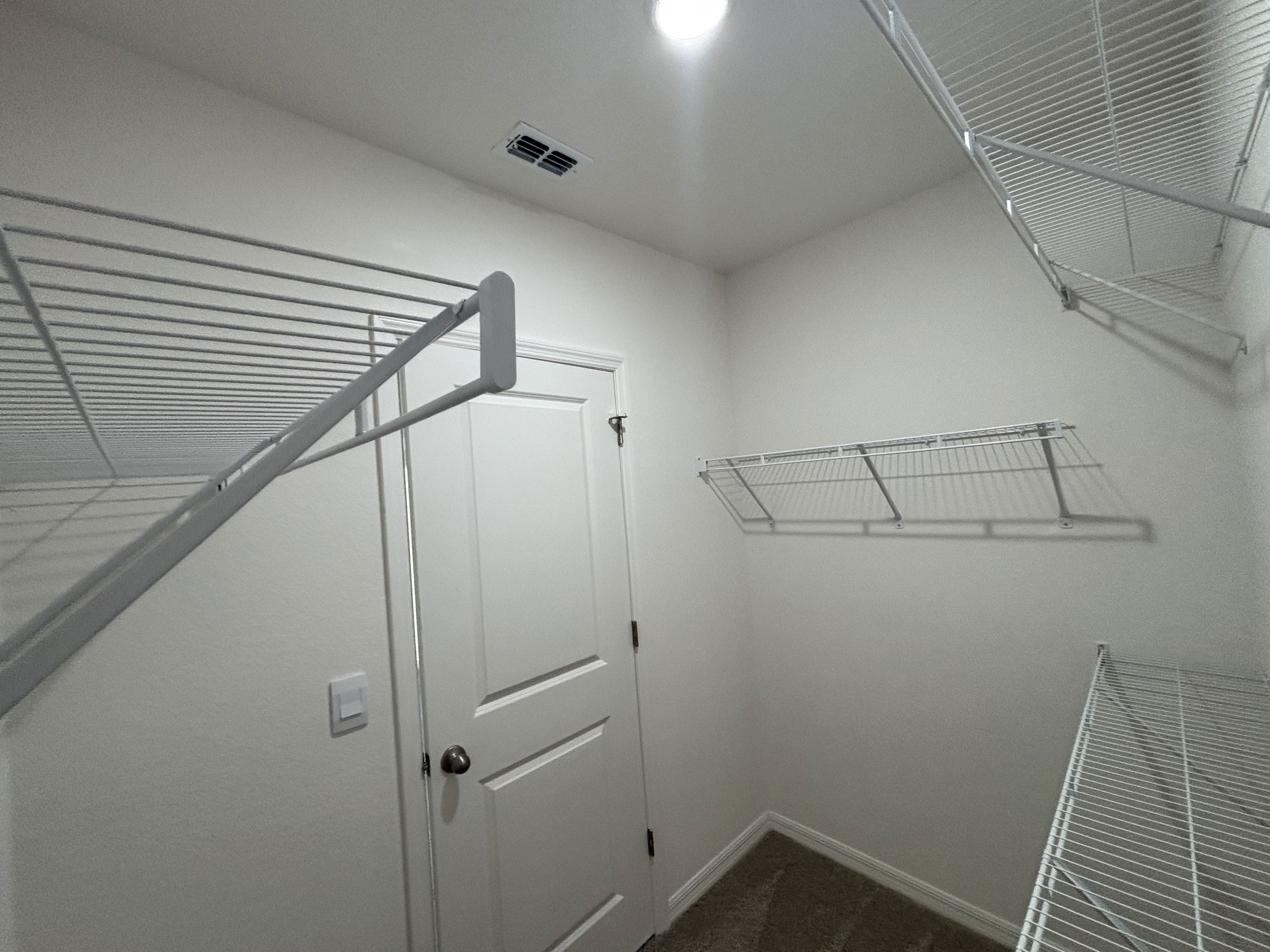 A well-organized walk-in closet featuring wire shelving and a white door.