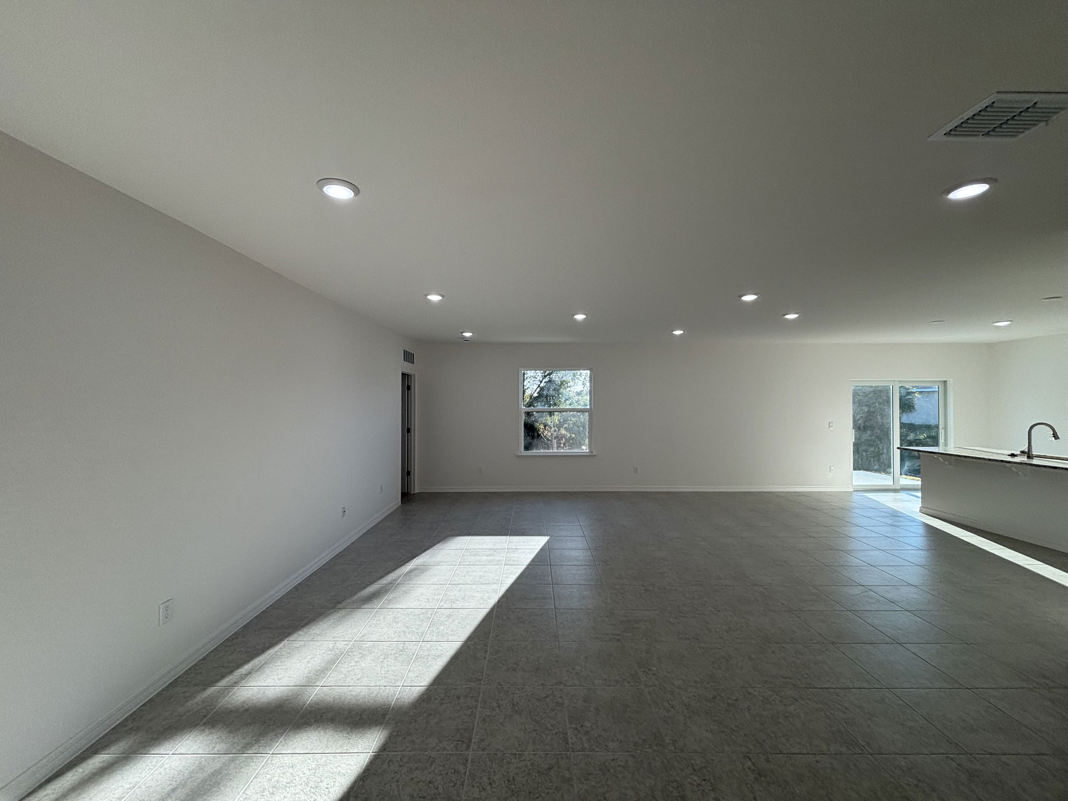 Spacious and bright living room with natural light, modern tile flooring, and neutral walls in a contemporary home.