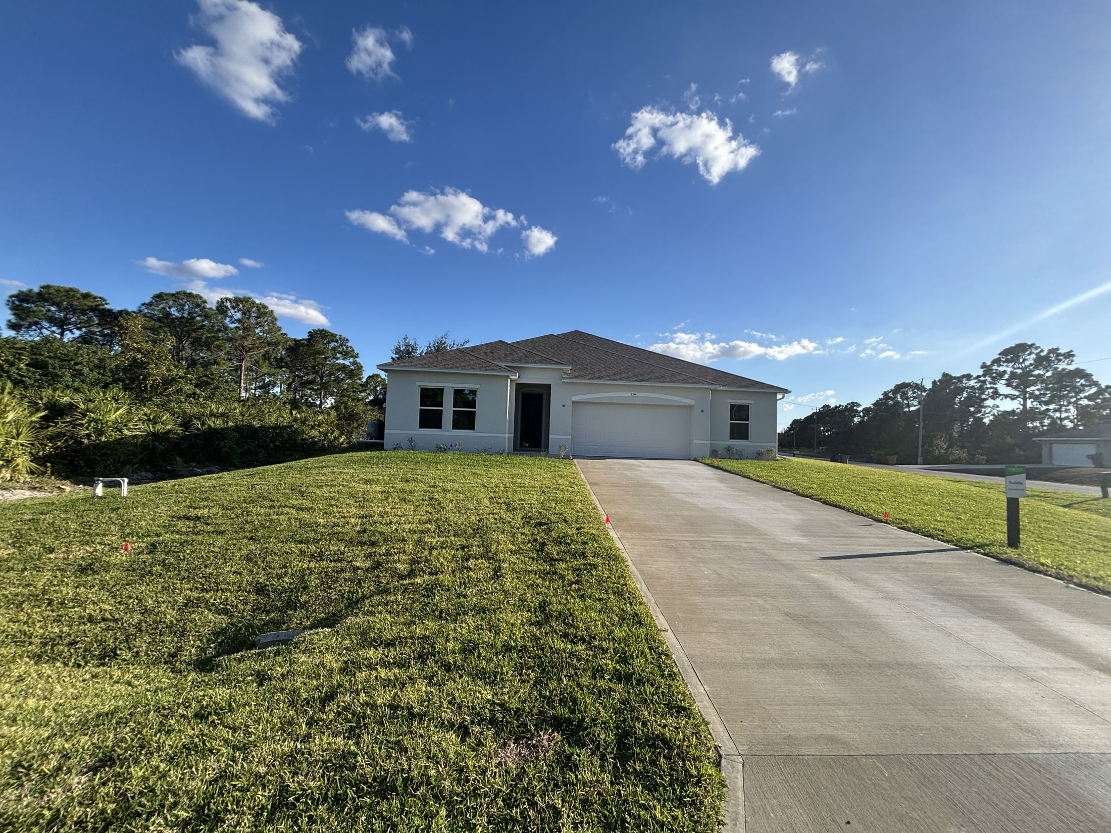 New modern house with lush green lawn and driveway under a clear blue sky.