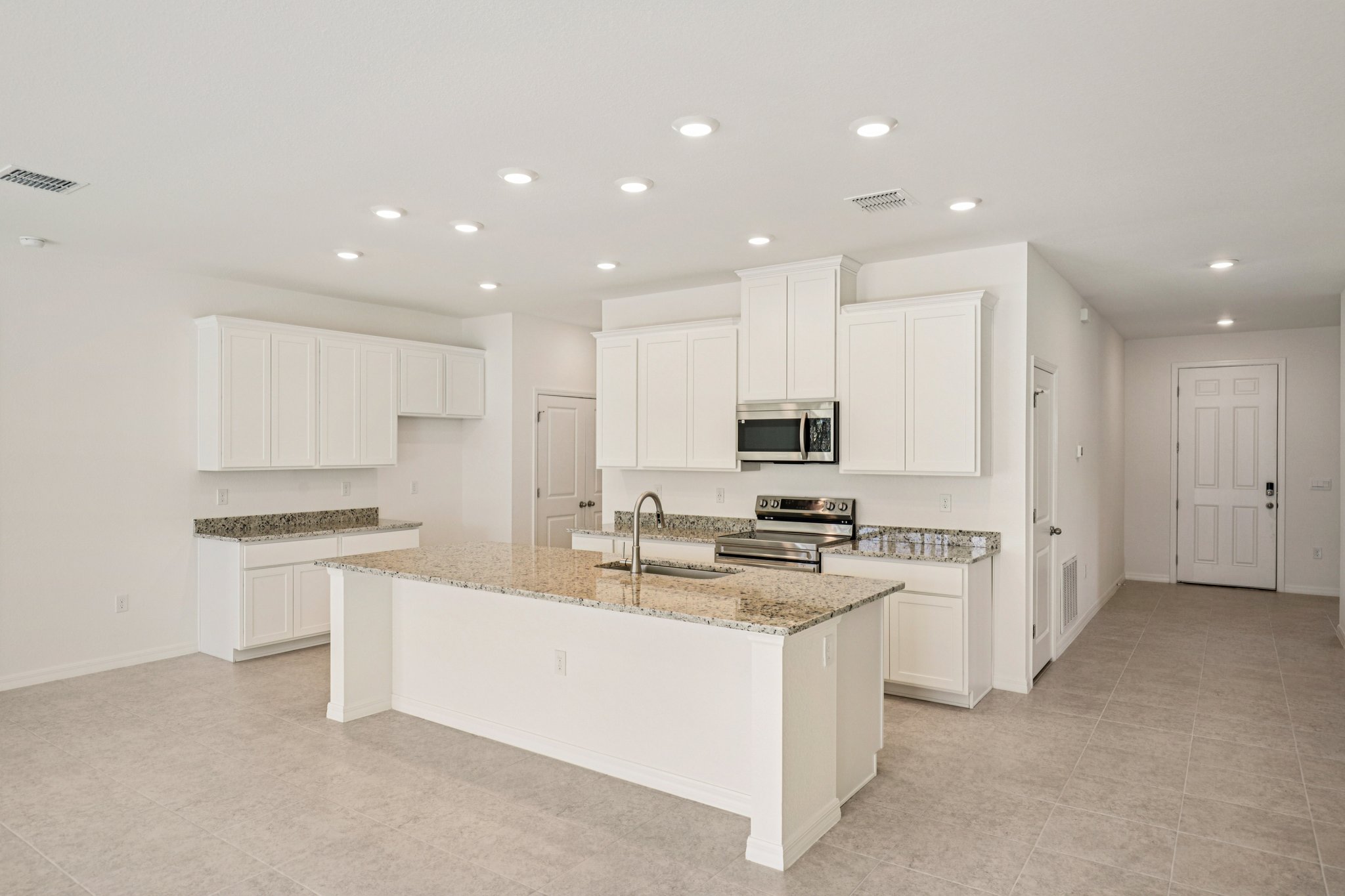Spacious modern kitchen featuring white cabinets, granite countertops, and stainless steel appliances in a bright, open layout.