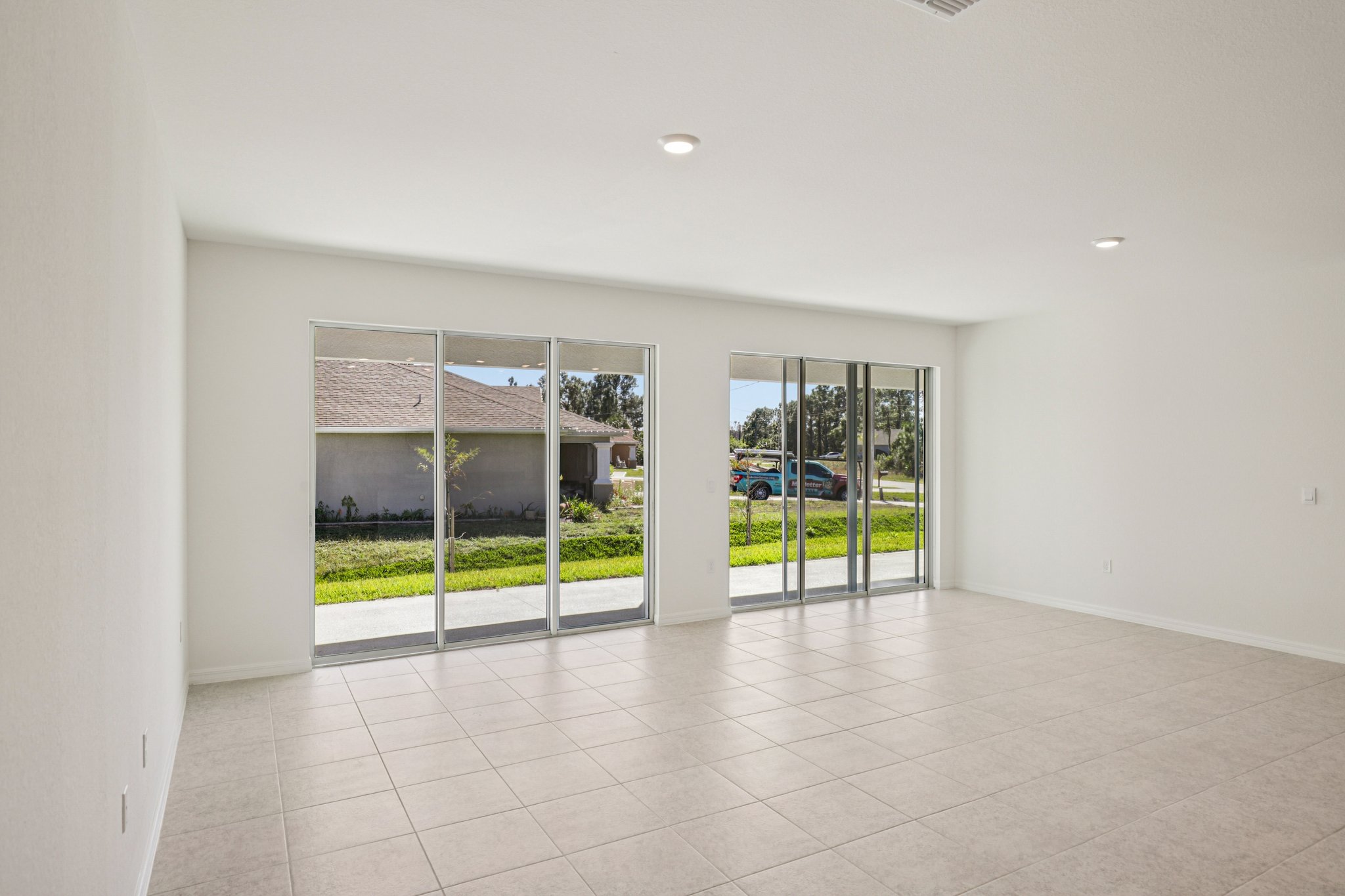 Bright and spacious living room with large sliding glass doors and neutral tile flooring.