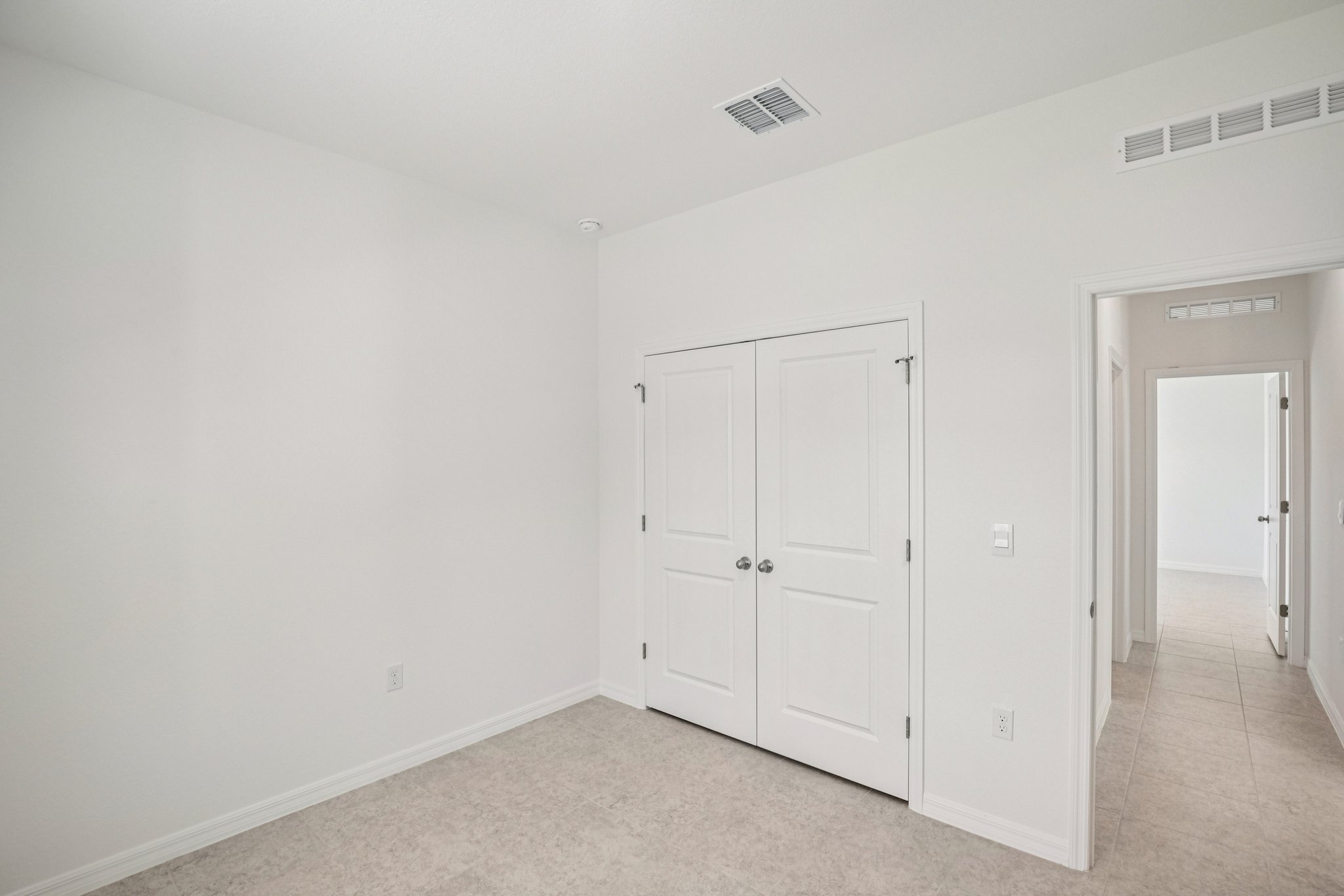 Bright and airy empty room with white walls and a double door closet, ideal for showcasing modern interior design.