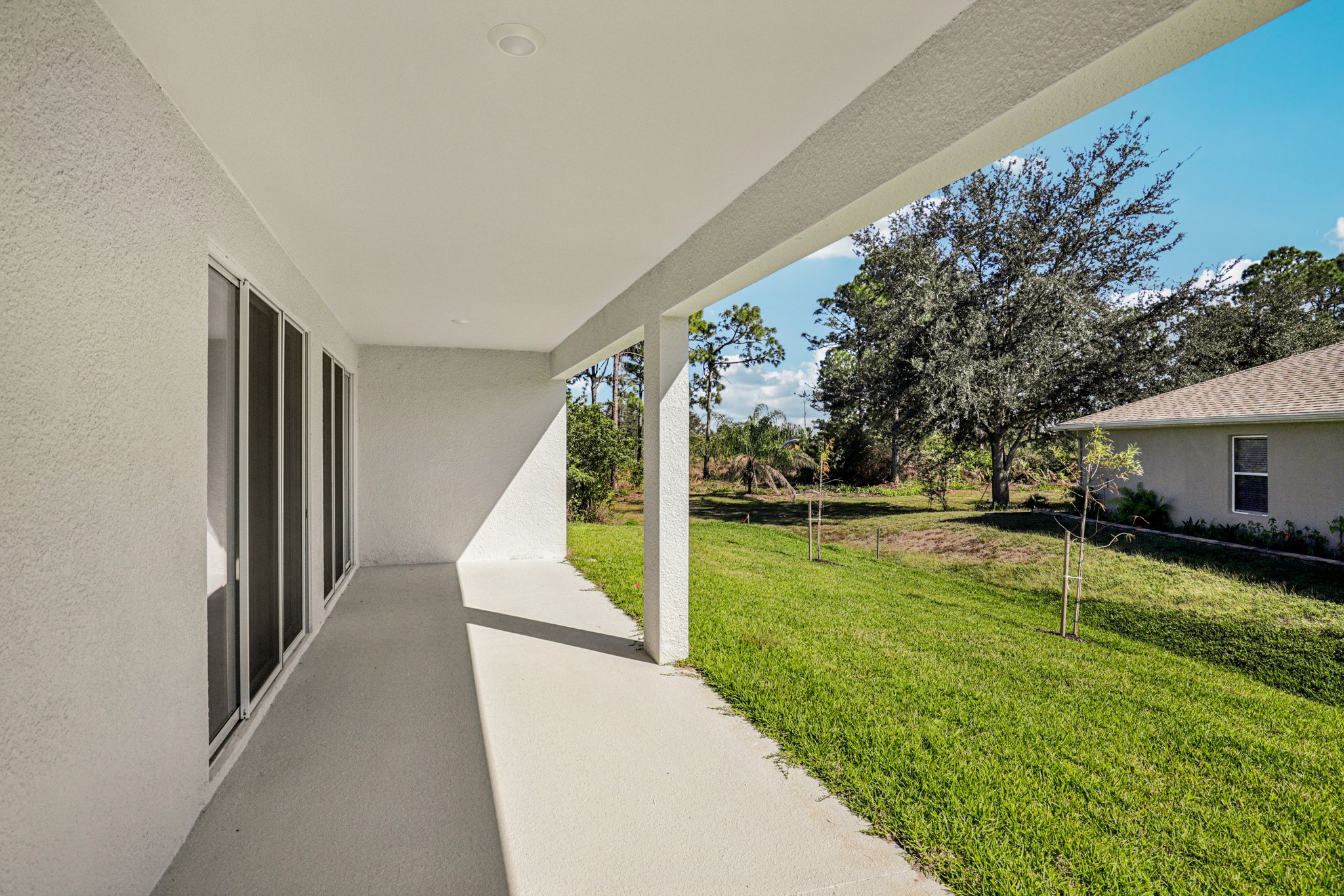 Spacious exterior patio area with a view of a lush green lawn and surrounding trees.