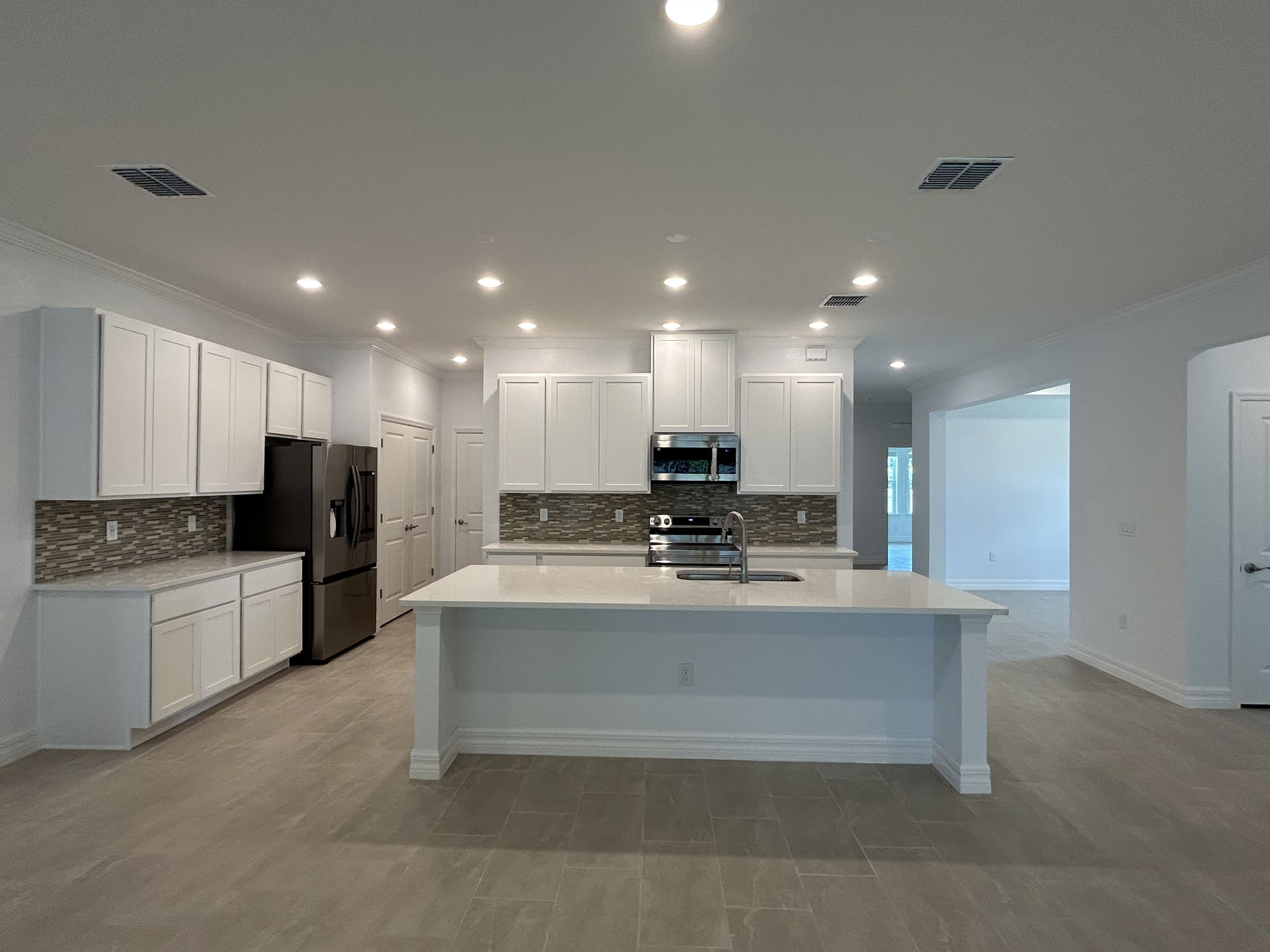 Modern kitchen with white cabinets, stainless steel appliances, and a large center island with built-in sink.