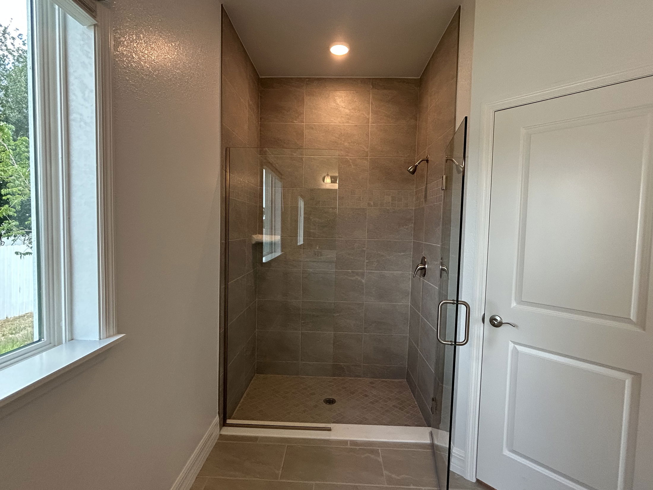 Modern bathroom featuring a spacious, glass-enclosed walk-in shower with elegant brown tile walls.