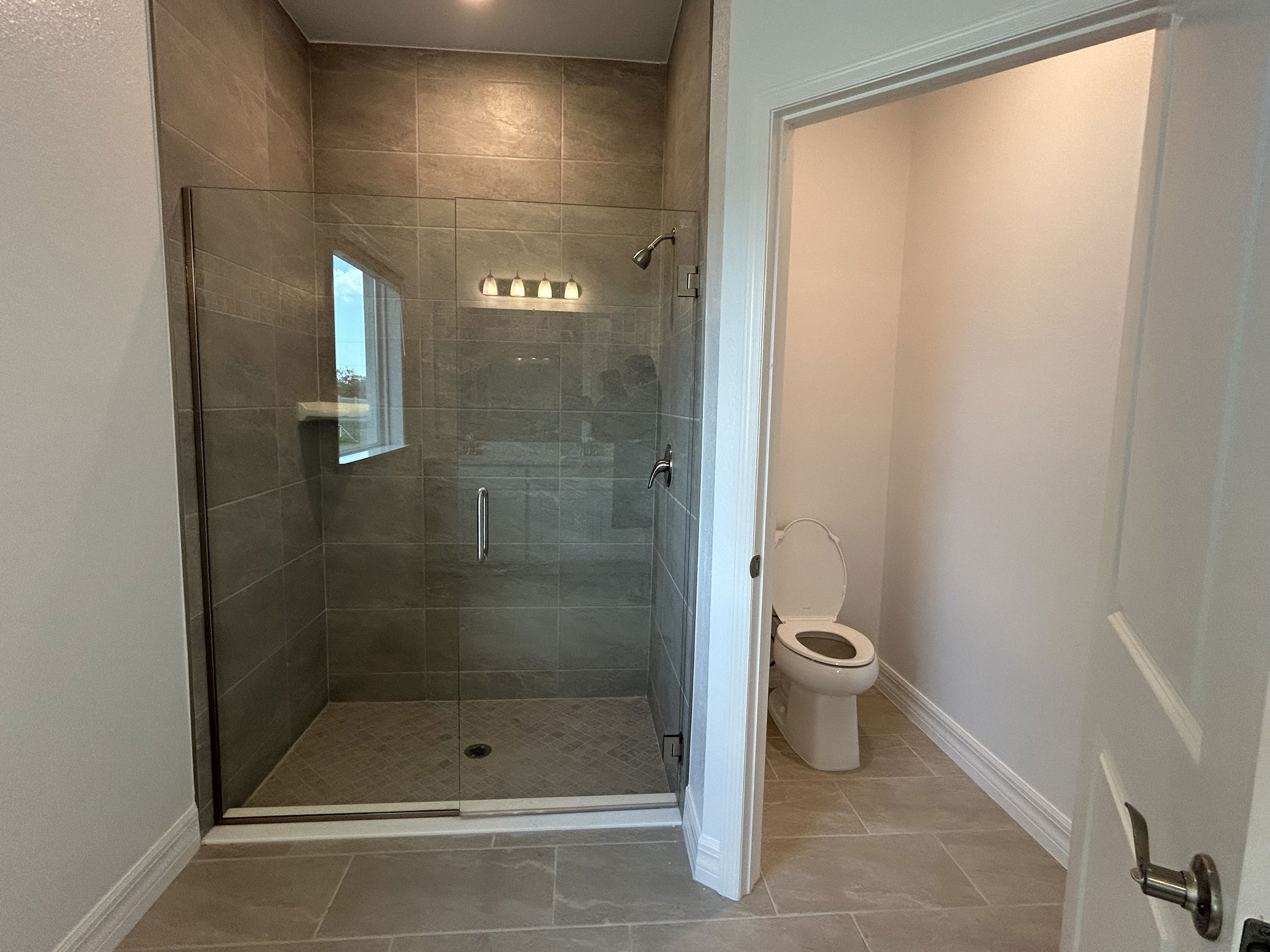 Modern bathroom with a glass-enclosed shower and adjacent toilet area.