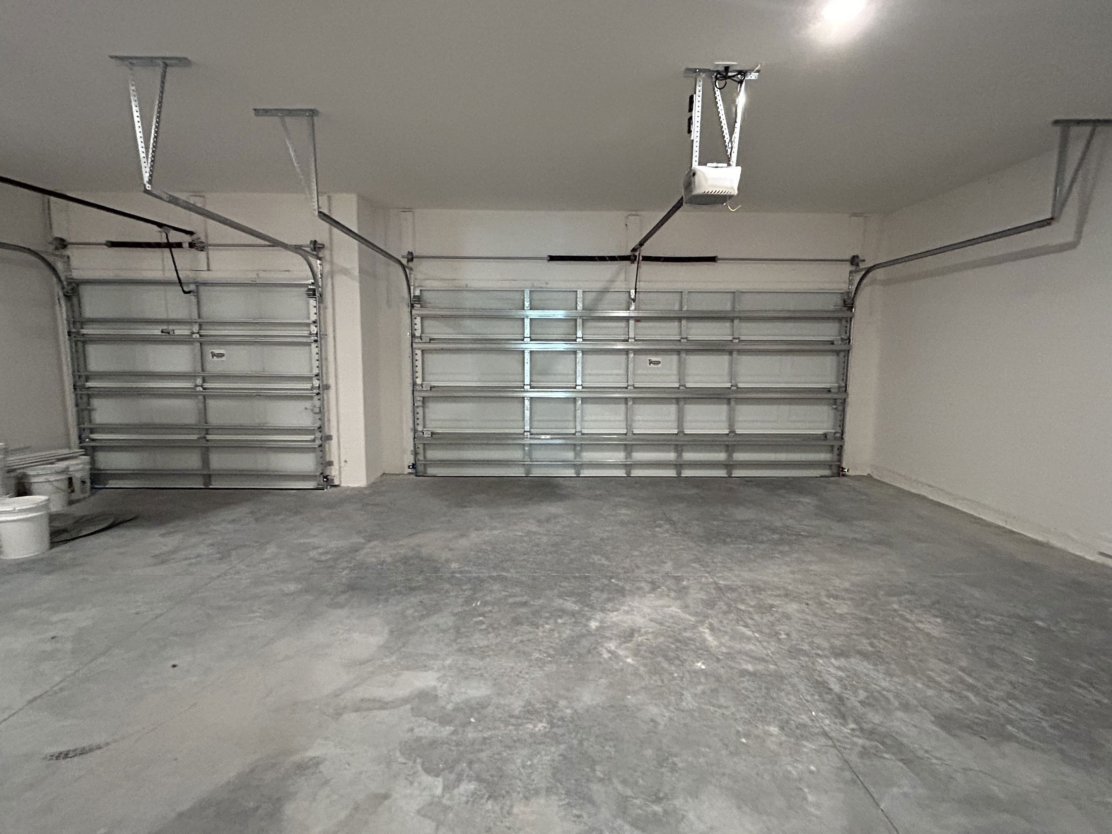 Spacious empty garage with two closed roller doors and concrete floor.