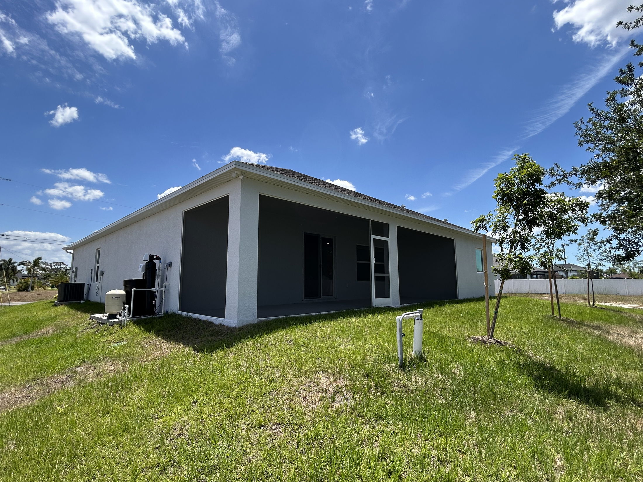 Modern one-story house with a grassy yard under a clear blue sky.