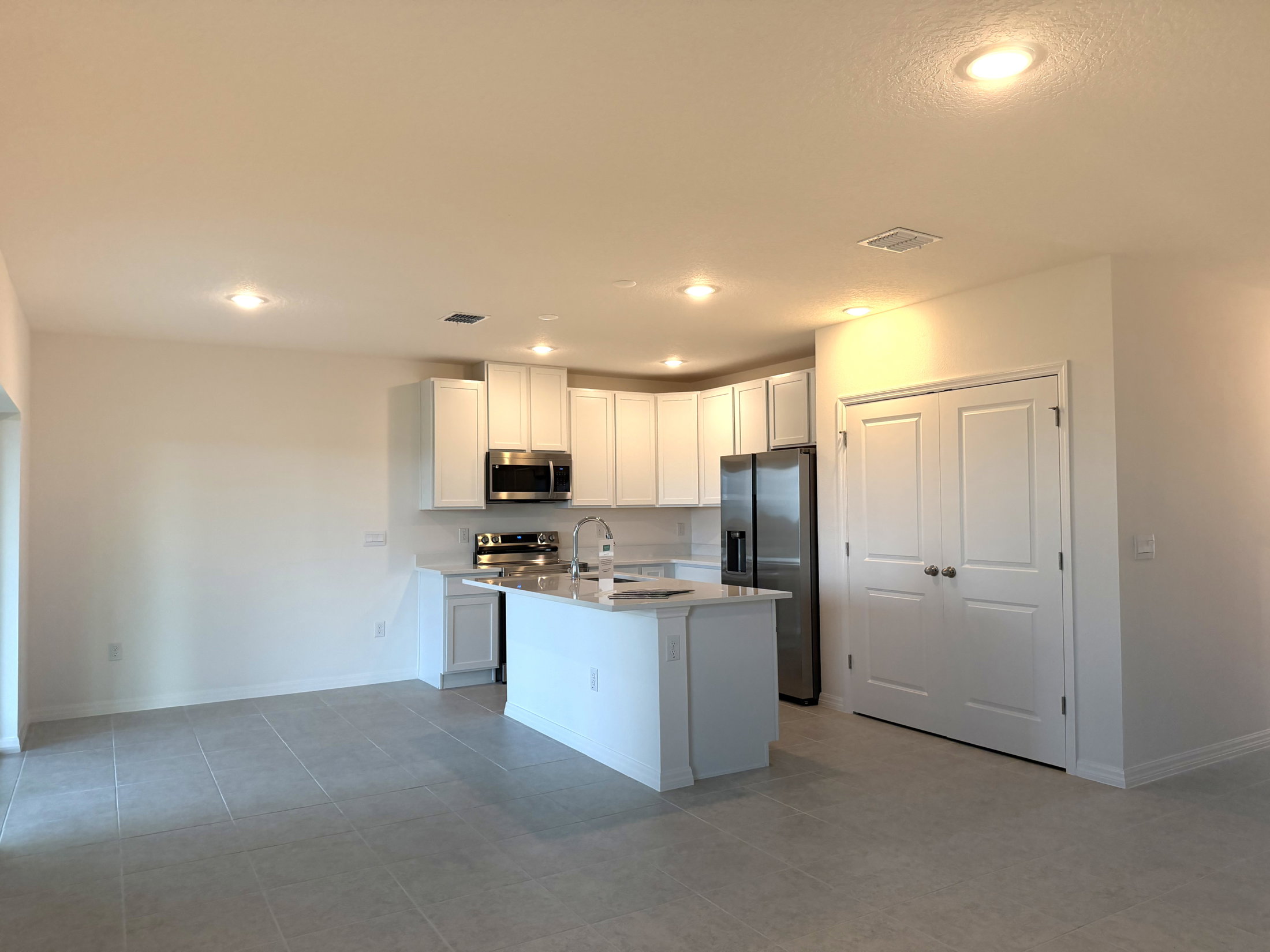 A modern kitchen featuring white cabinets, stainless steel appliances, and a central island with a sink.