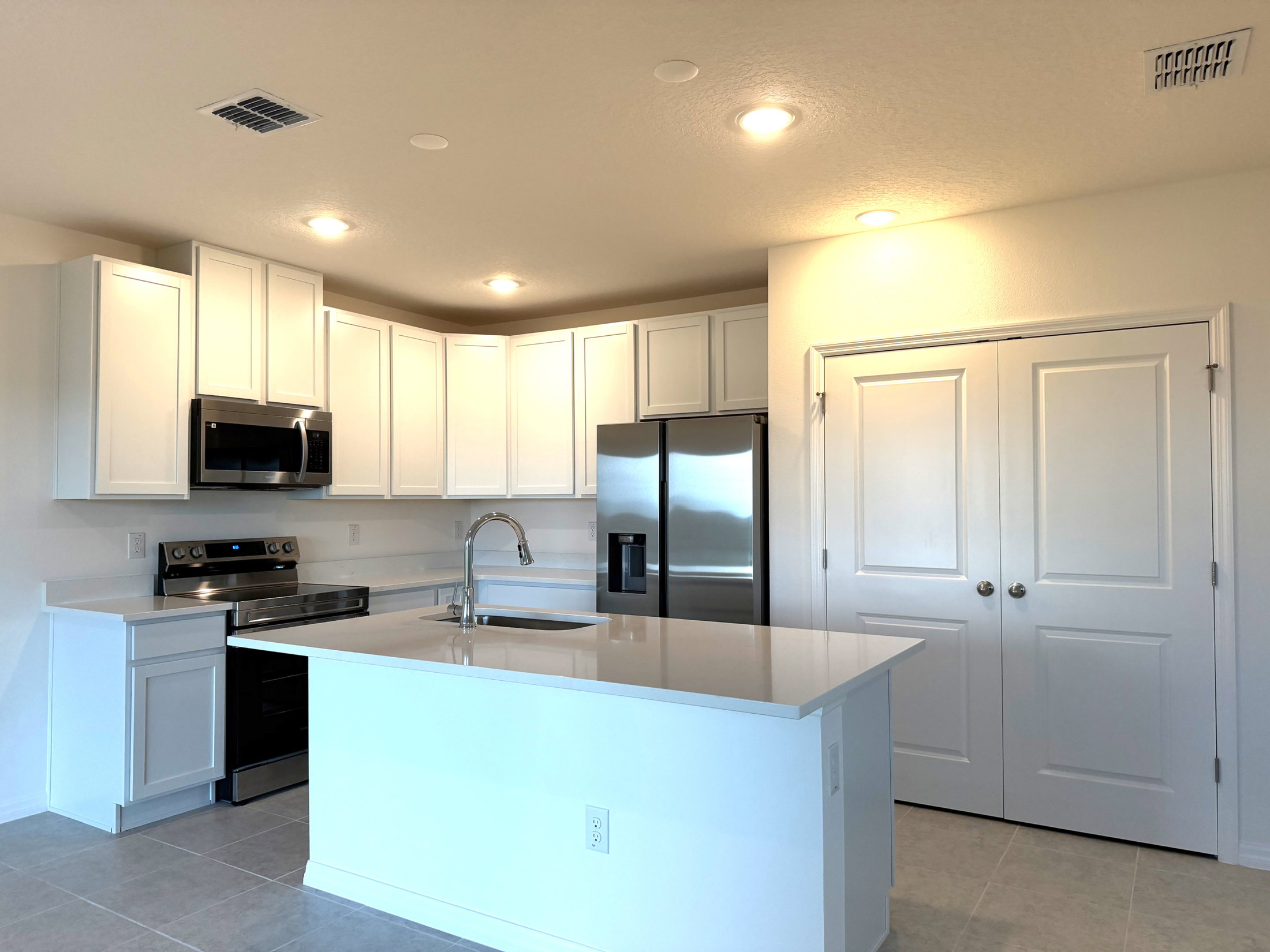 Modern kitchen featuring white cabinetry, stainless steel appliances, and a central island with a sink.