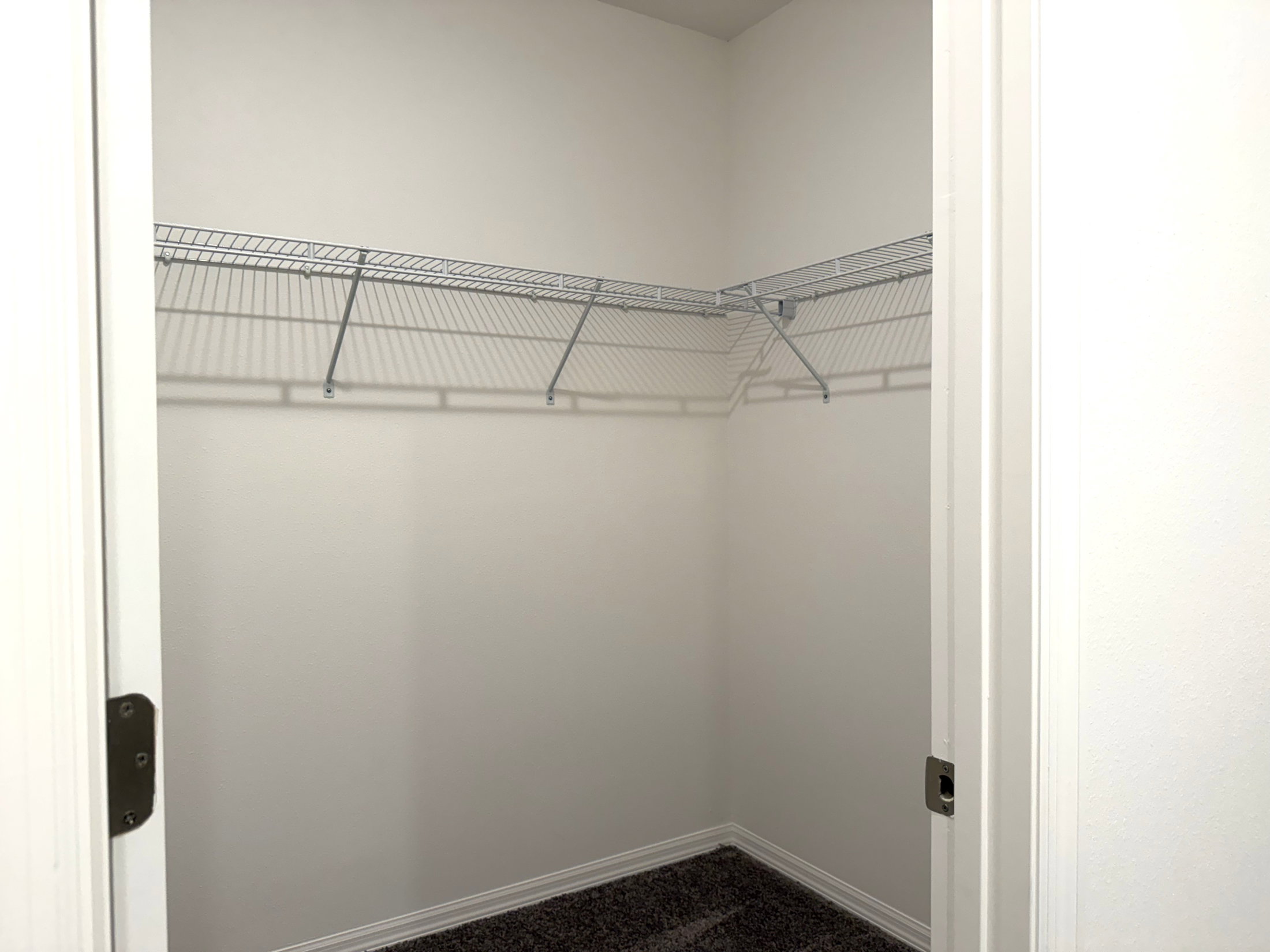 Empty closet with a wire shelf and light-colored walls.