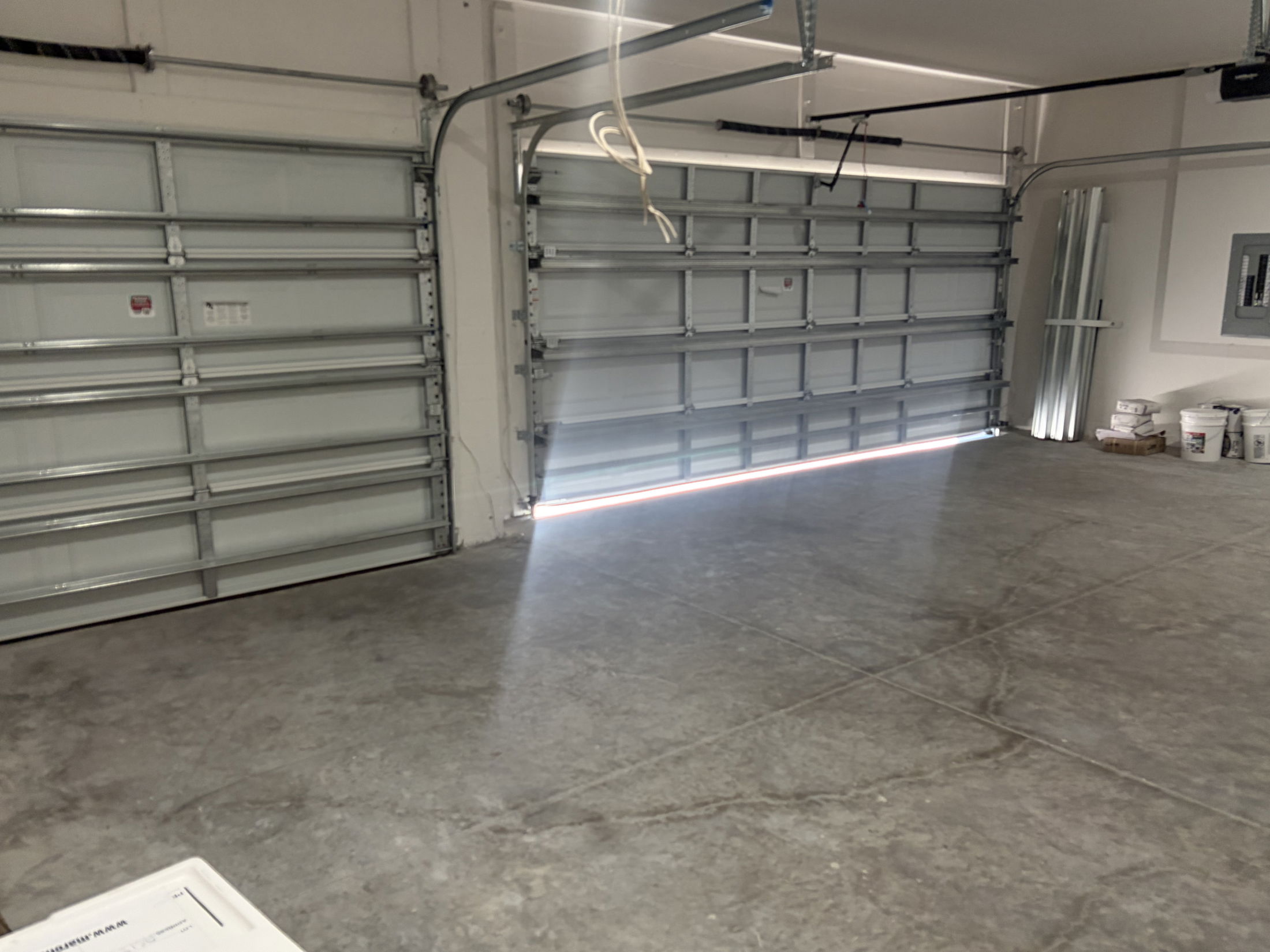 Spacious and well-lit garage interior featuring two large garage doors and a concrete floor.