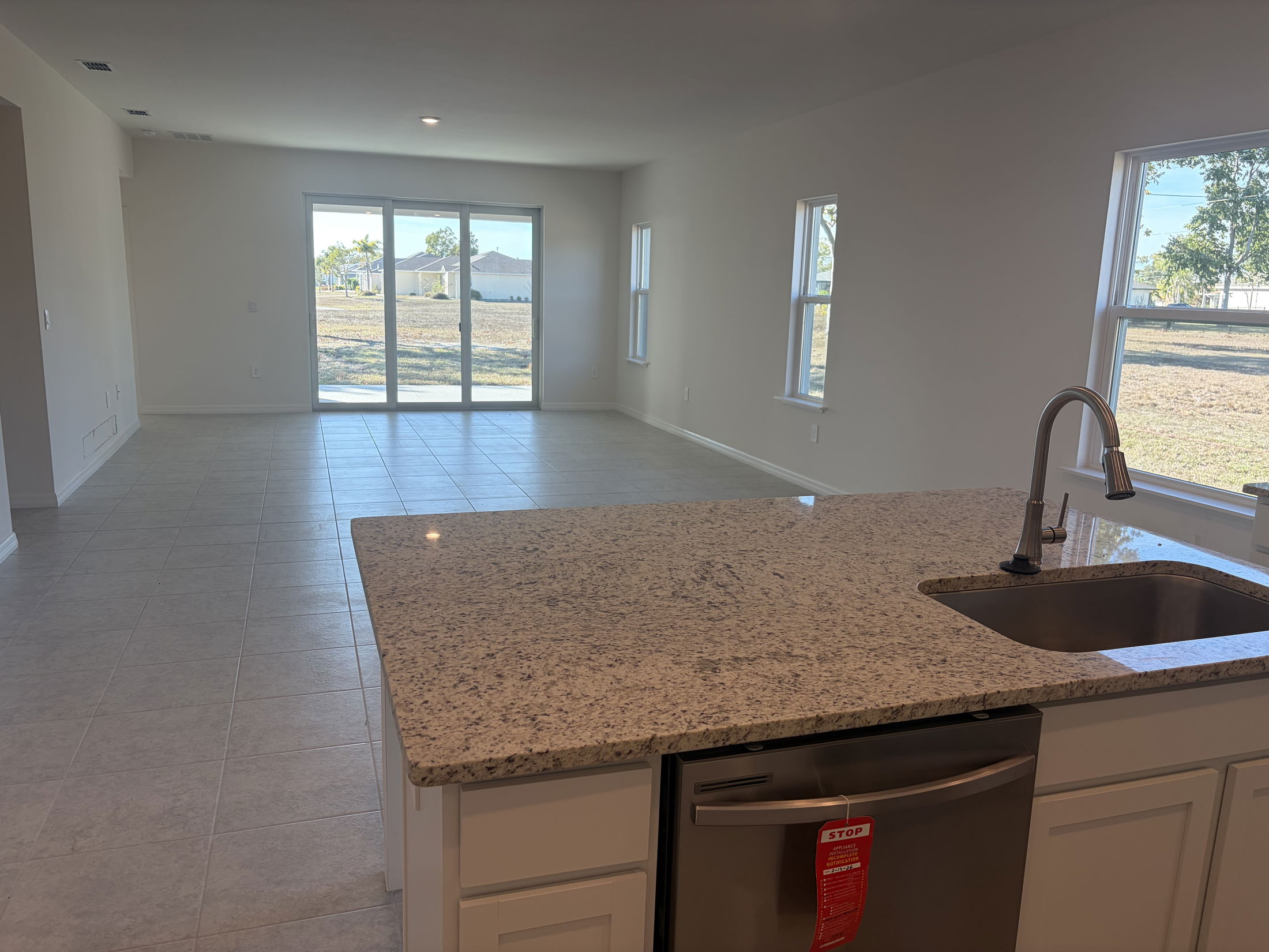 Modern open-concept living space featuring a kitchen island, stainless steel appliances, and natural light from large windows.