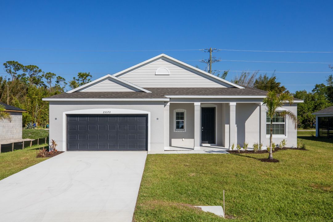 Modern single-story home with a light gray exterior, dark garage door, and manicured lawn on a clear day.