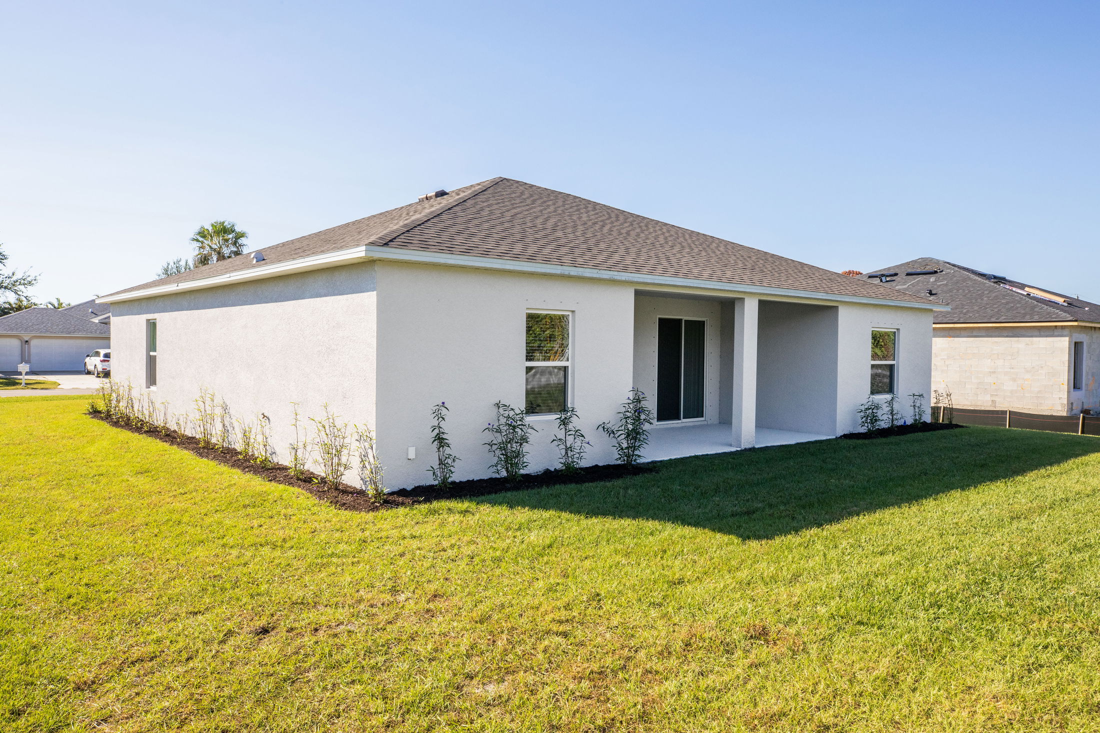 Modern single-story home with a gray roof and neatly landscaped backyard.