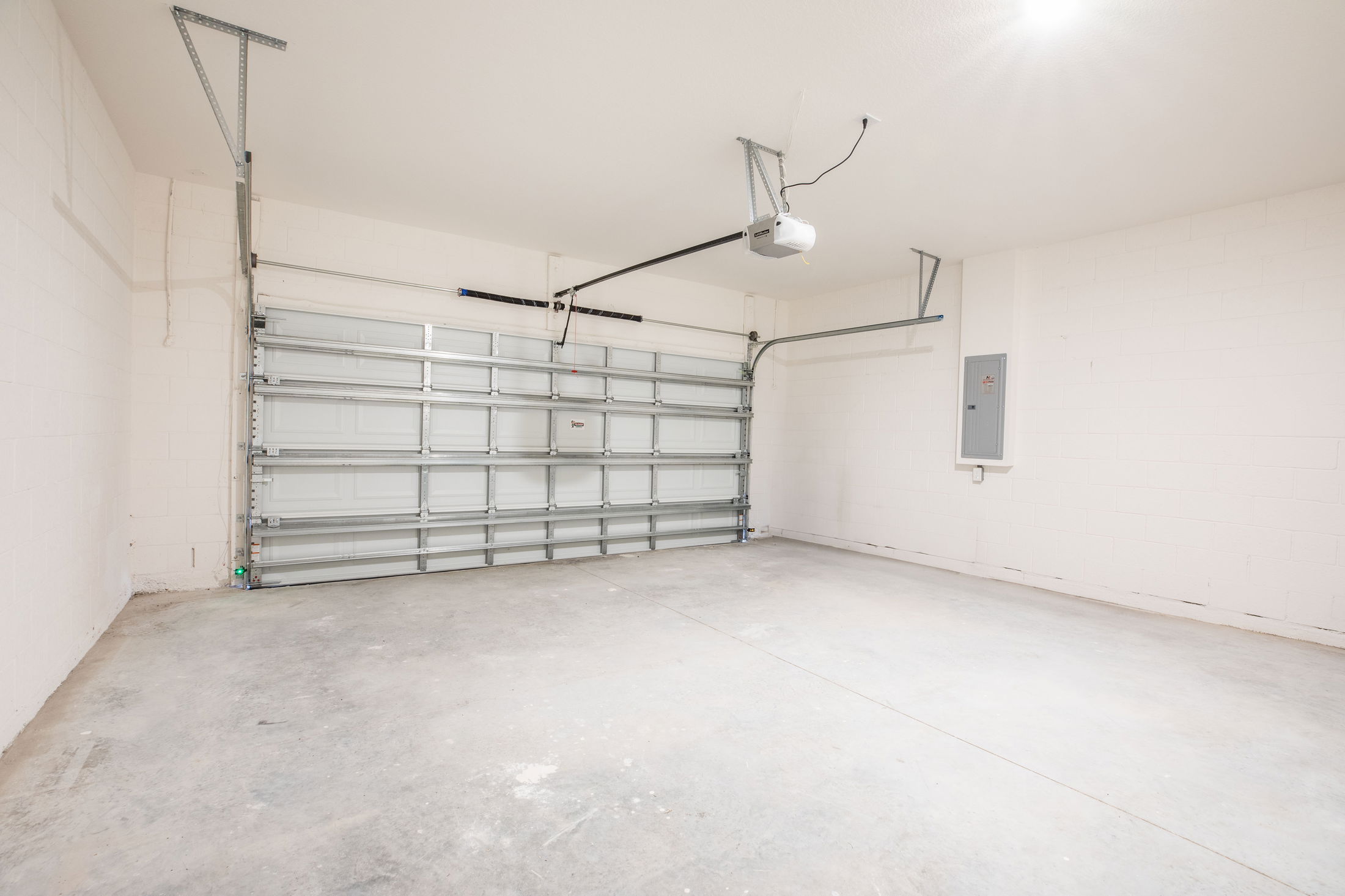 Empty garage with a clean concrete floor and a closed automatic garage door.