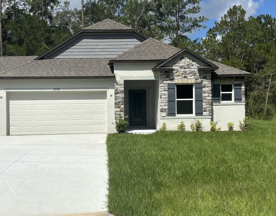 Single-story house with a stone-accented front, green lawn, and a paved driveway.