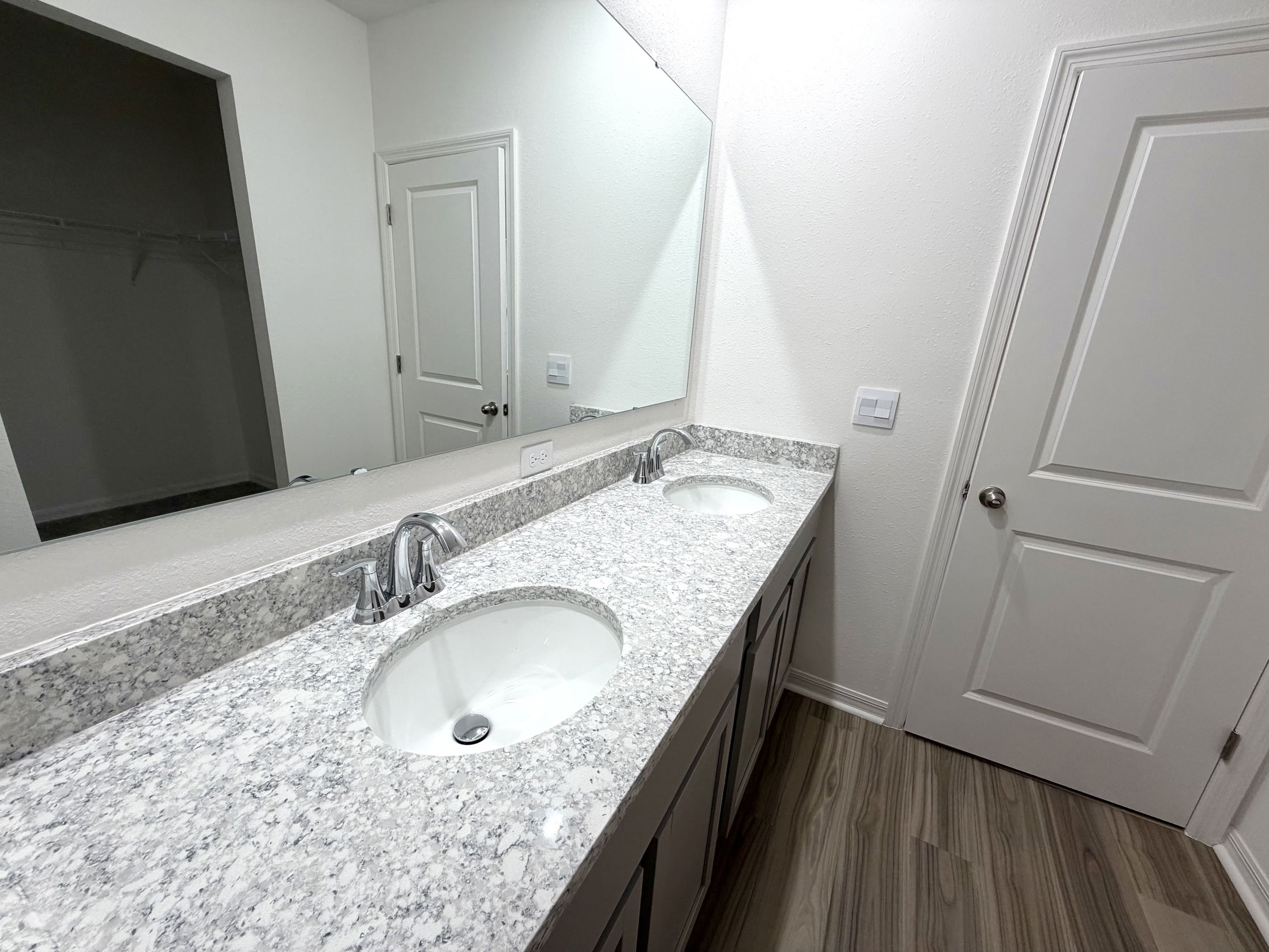 Modern bathroom with double sink vanity, granite countertop, and neutral-colored walls.