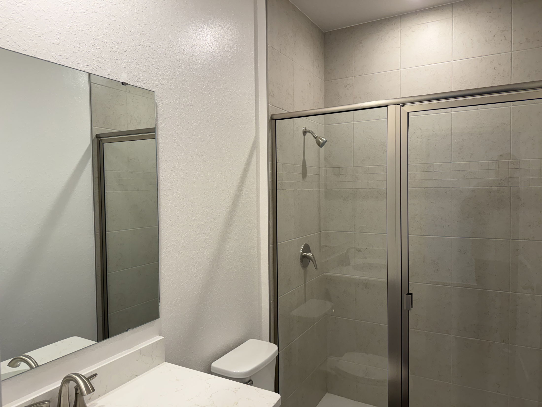 Modern bathroom interior featuring a sleek shower stall, a large mirror, and minimalist decor.