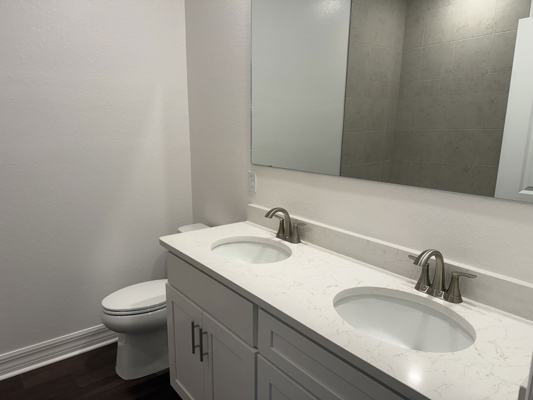Modern bathroom with double sink vanity, large mirror, and neutral-colored walls.