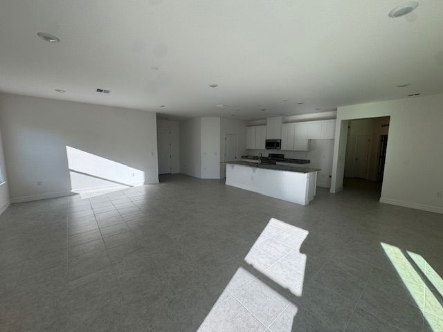 Spacious open-concept living area with tile flooring and natural light streaming in from large windows.