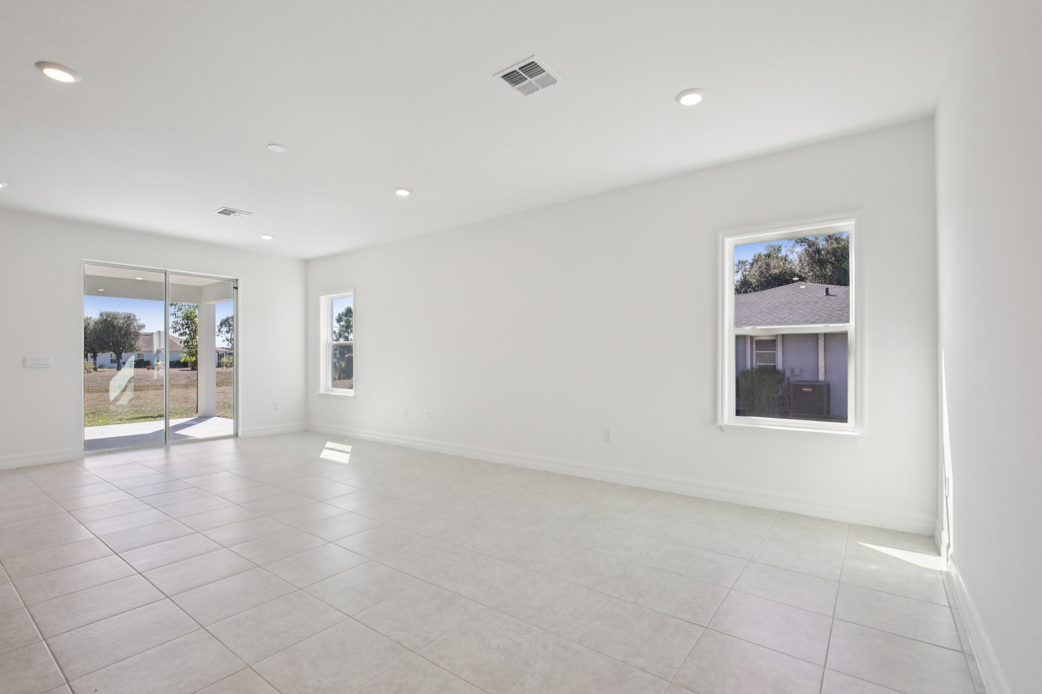 Bright and spacious living room with large windows and sliding door opening to a patio.