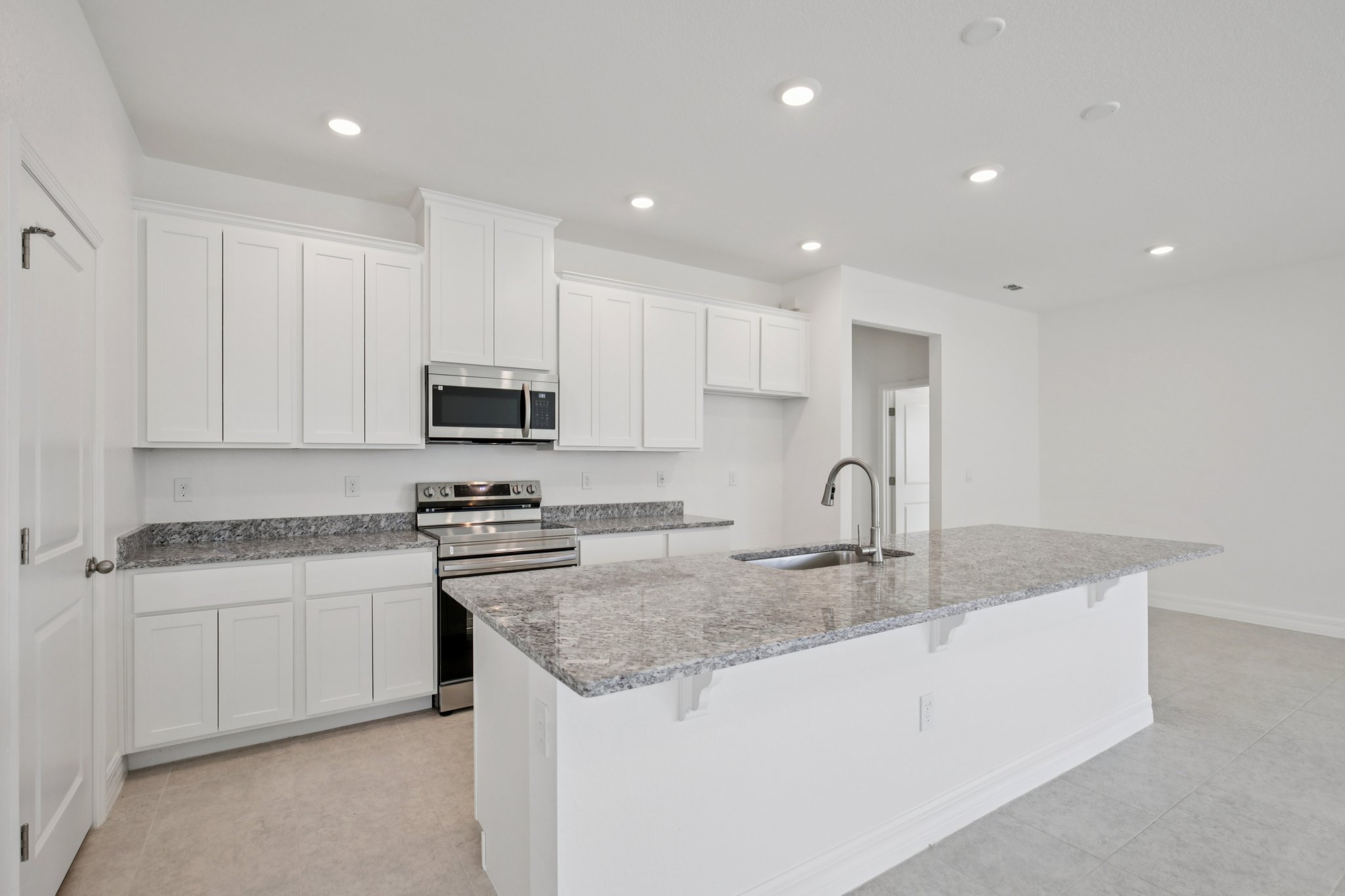 Modern kitchen interior featuring white cabinetry, stainless steel appliances, and granite countertops.