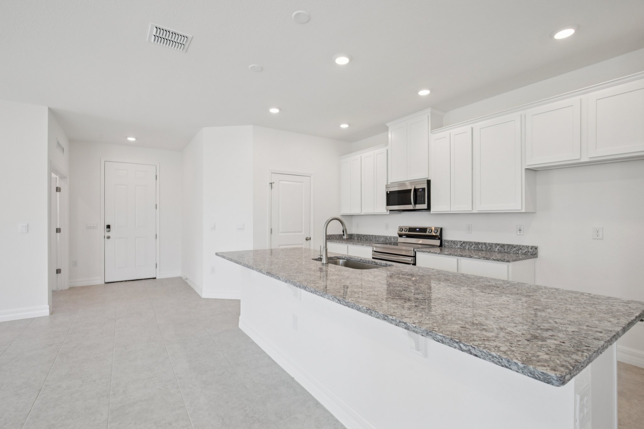 Modern kitchen with white cabinetry, stainless steel appliances, and granite countertops in a bright, open layout.