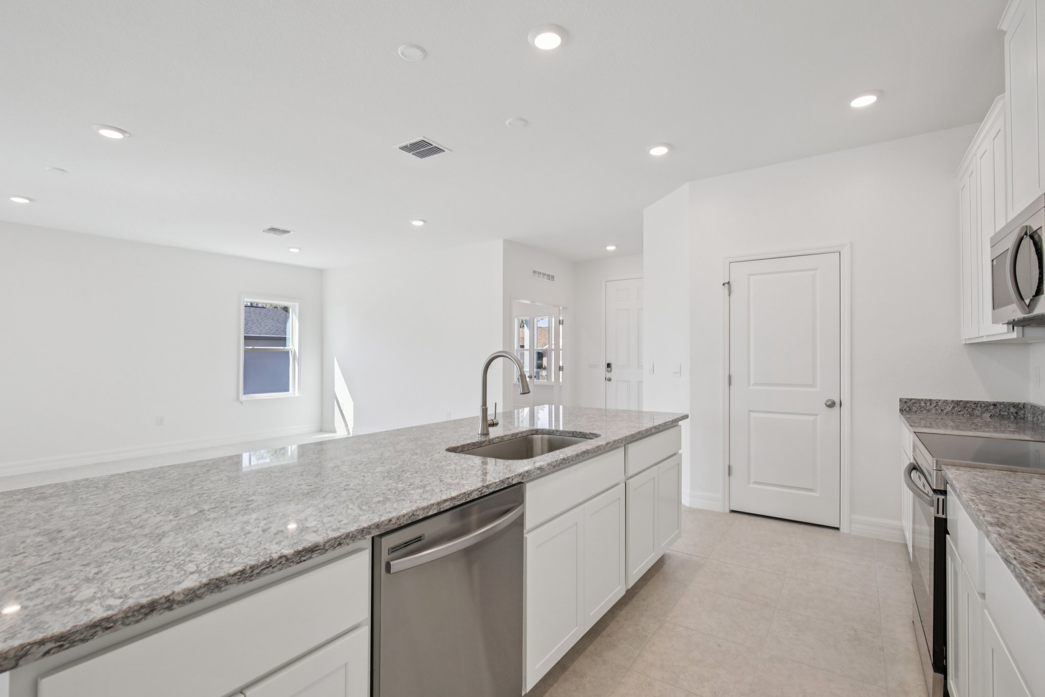 Modern kitchen featuring sleek granite countertops, stainless steel appliances, and bright white cabinetry in a spacious, open layout.