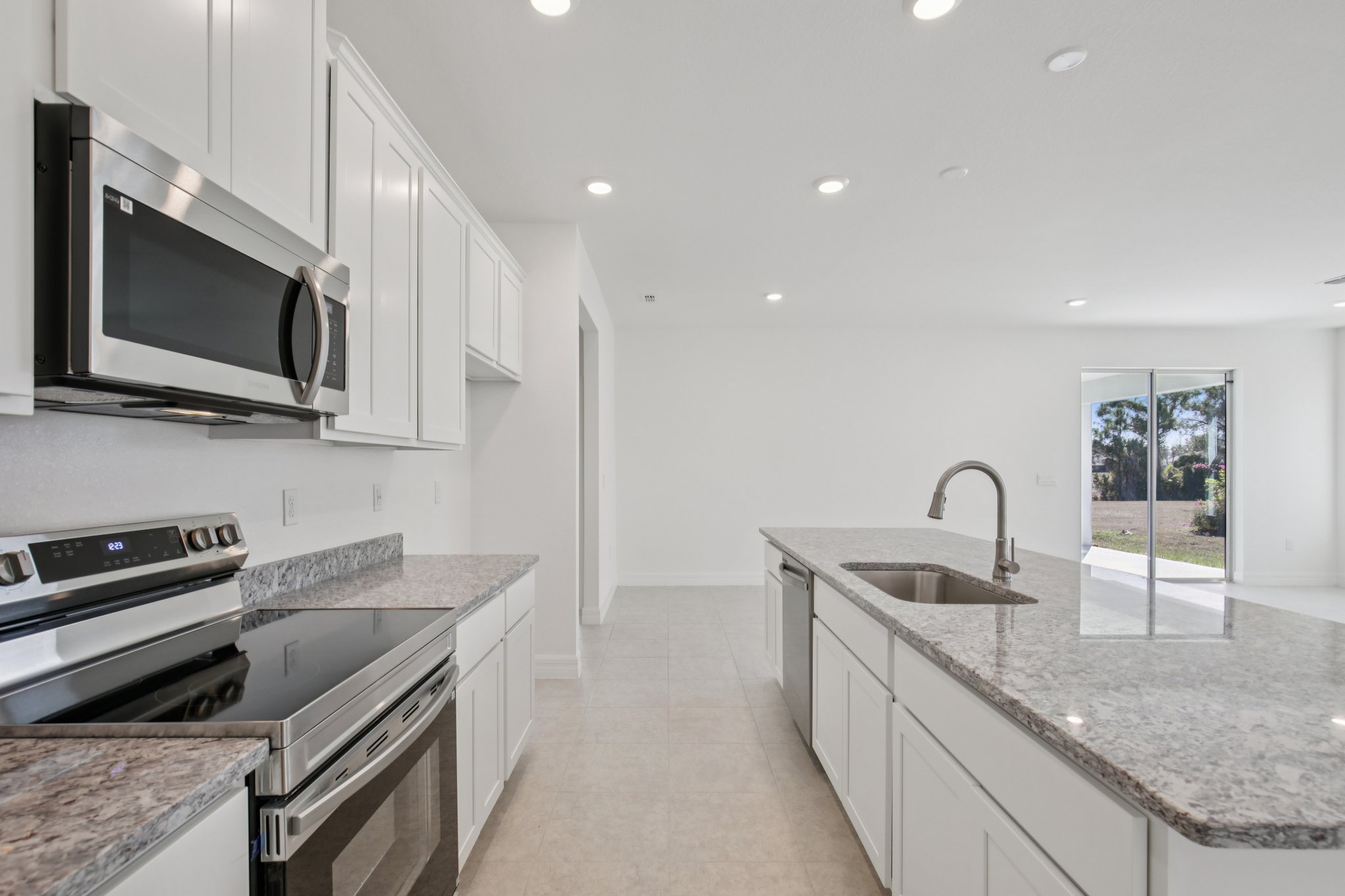 Modern kitchen featuring stainless steel appliances, granite countertops, and white cabinetry with an open layout.