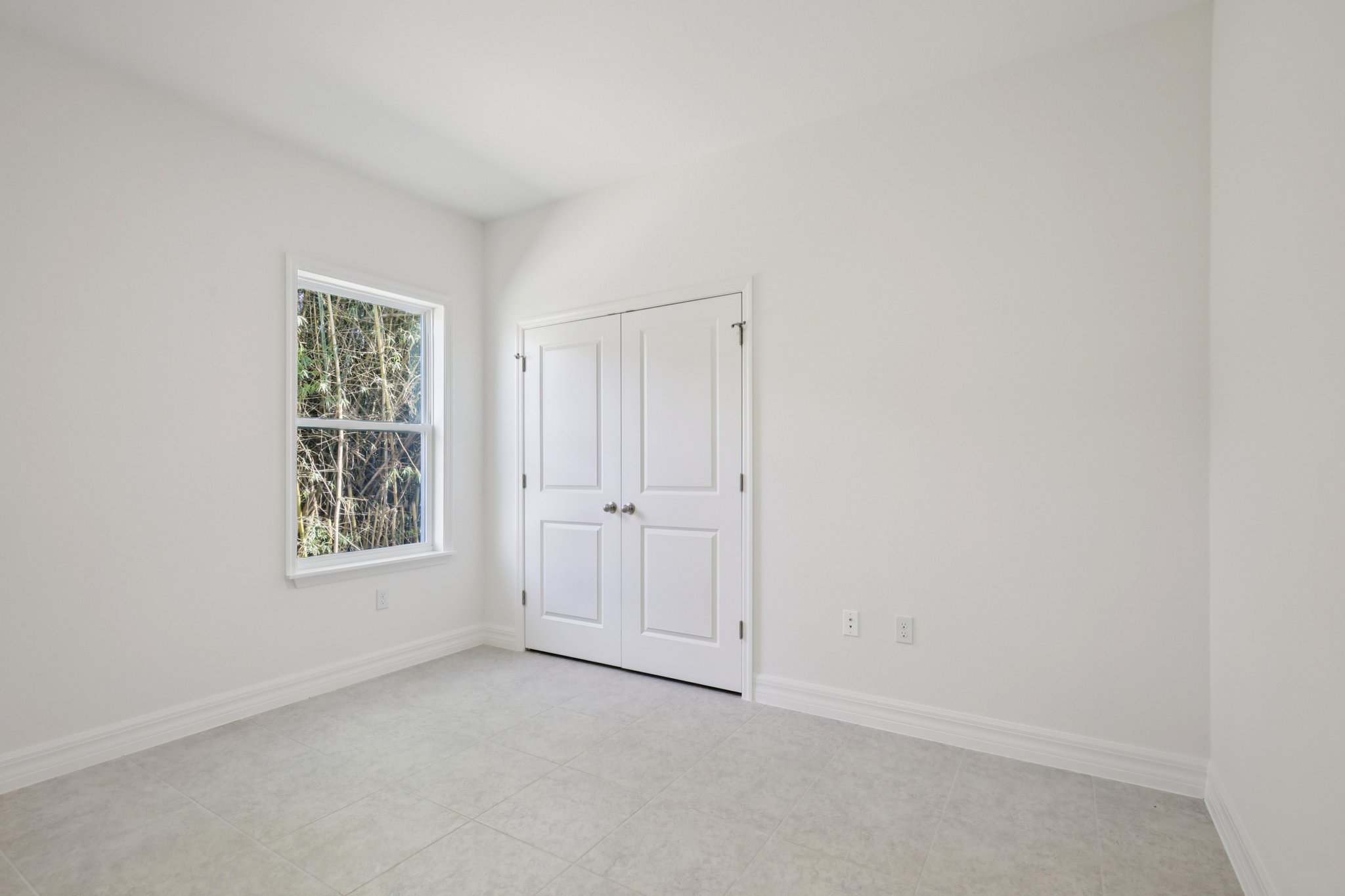 Empty modern room with white walls, a window, and double doors.