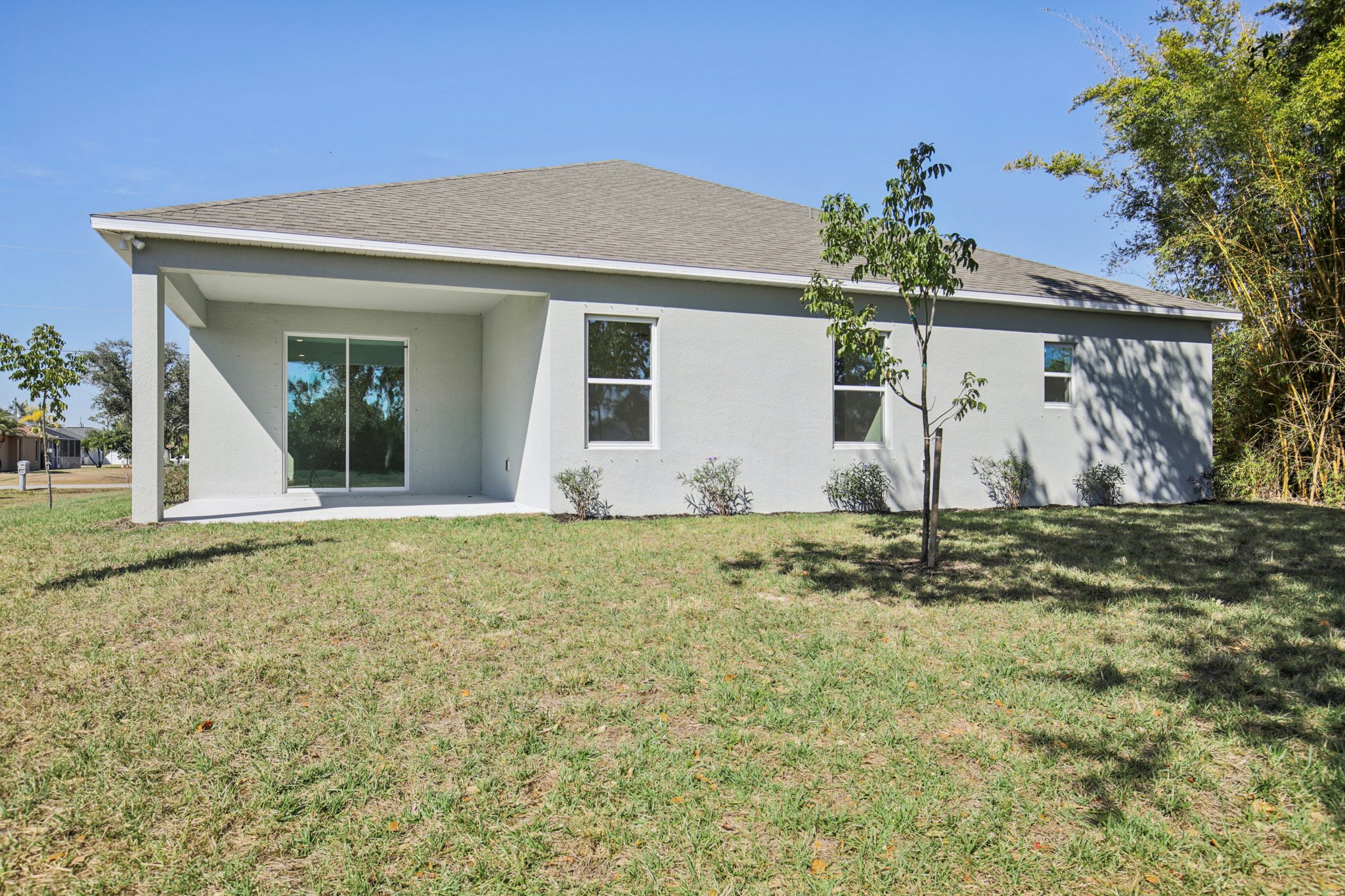 Single-story modern house with a manicured lawn and large sliding glass doors.