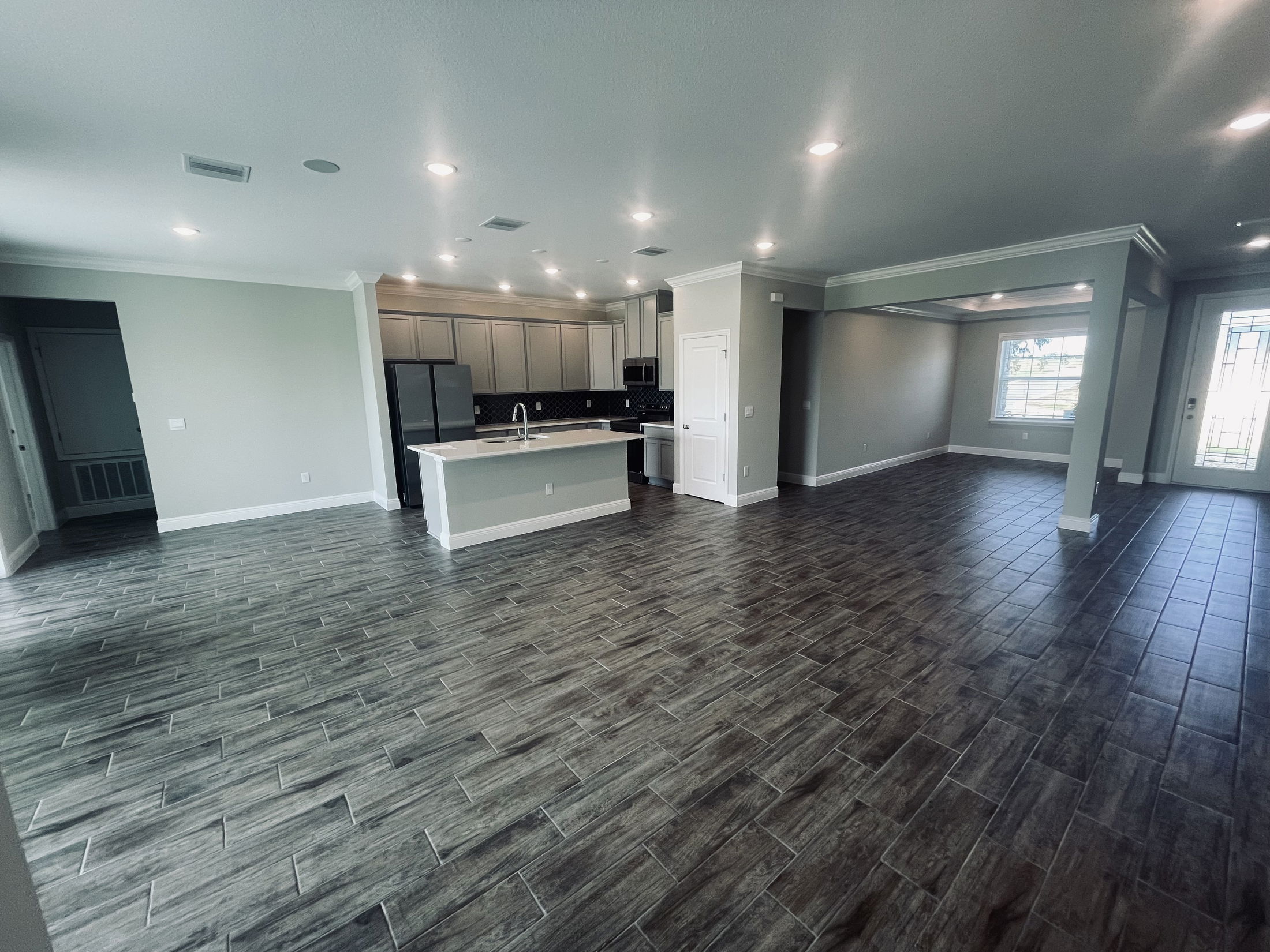 Spacious open-concept kitchen and living area with tiled flooring and modern lighting.