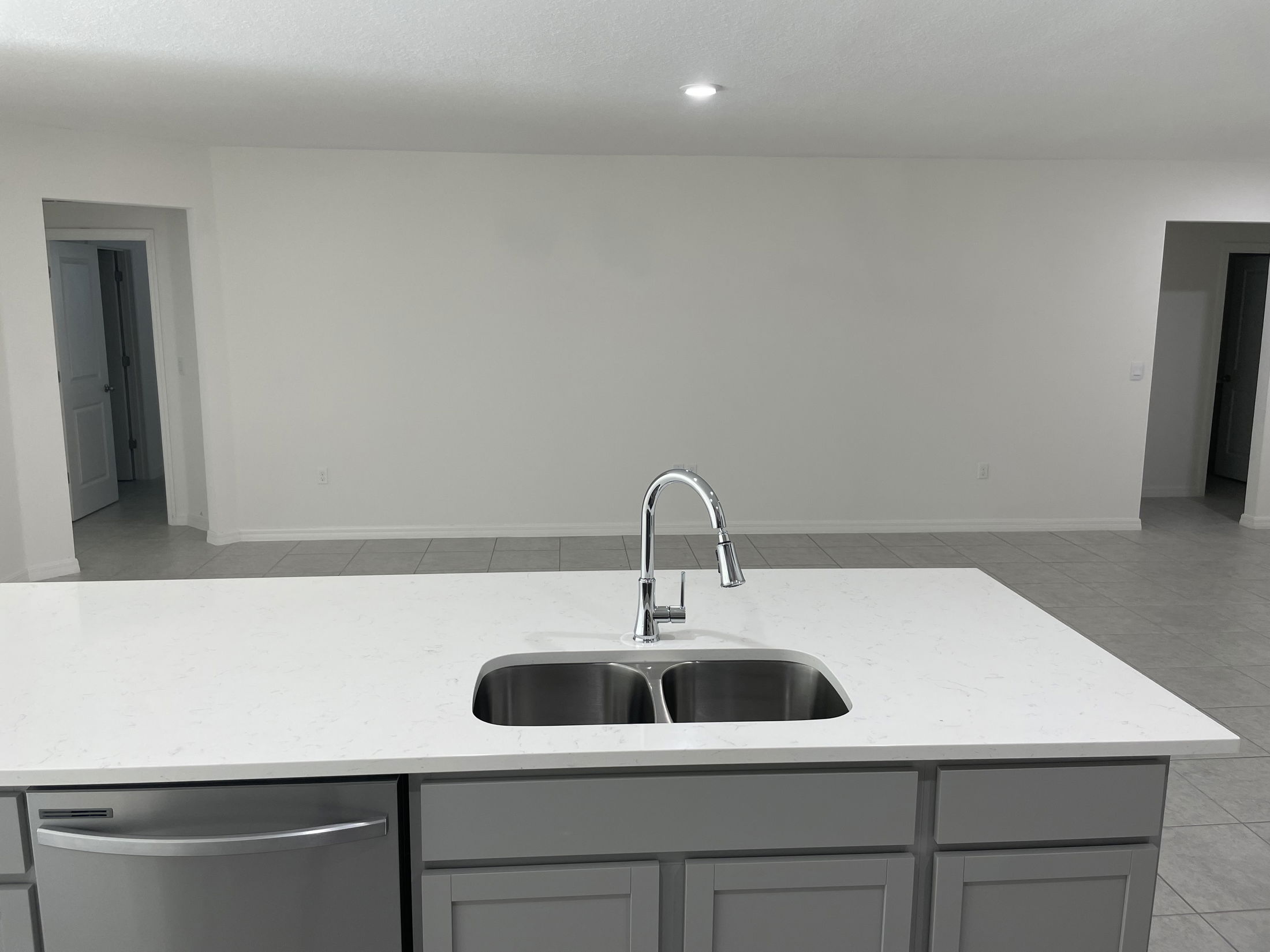 Modern kitchen island with a dual sink and stainless steel dishwasher in a minimalist, open-concept space.