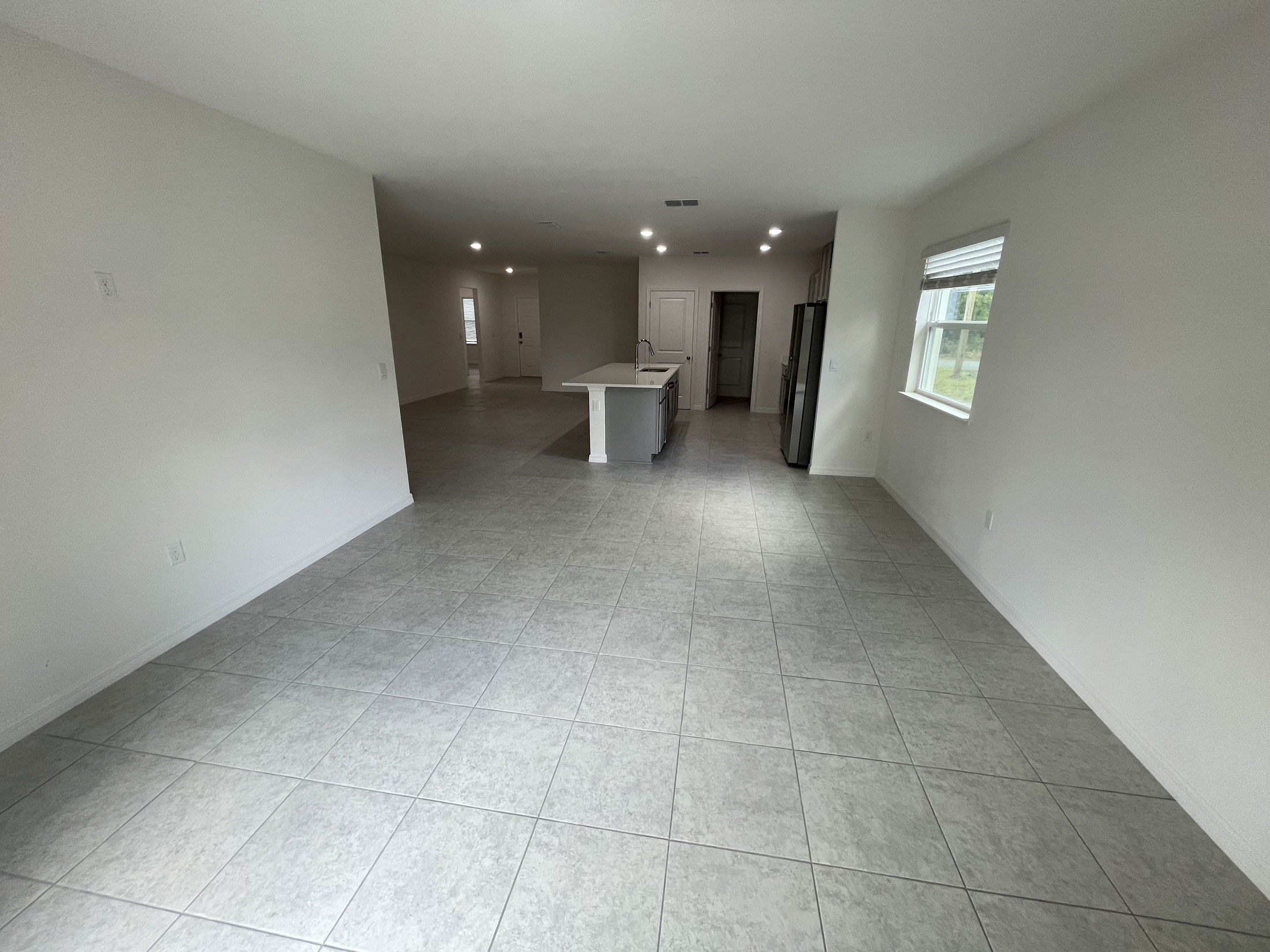 Spacious, modern open-concept living area with tiled floors and a central kitchen island.