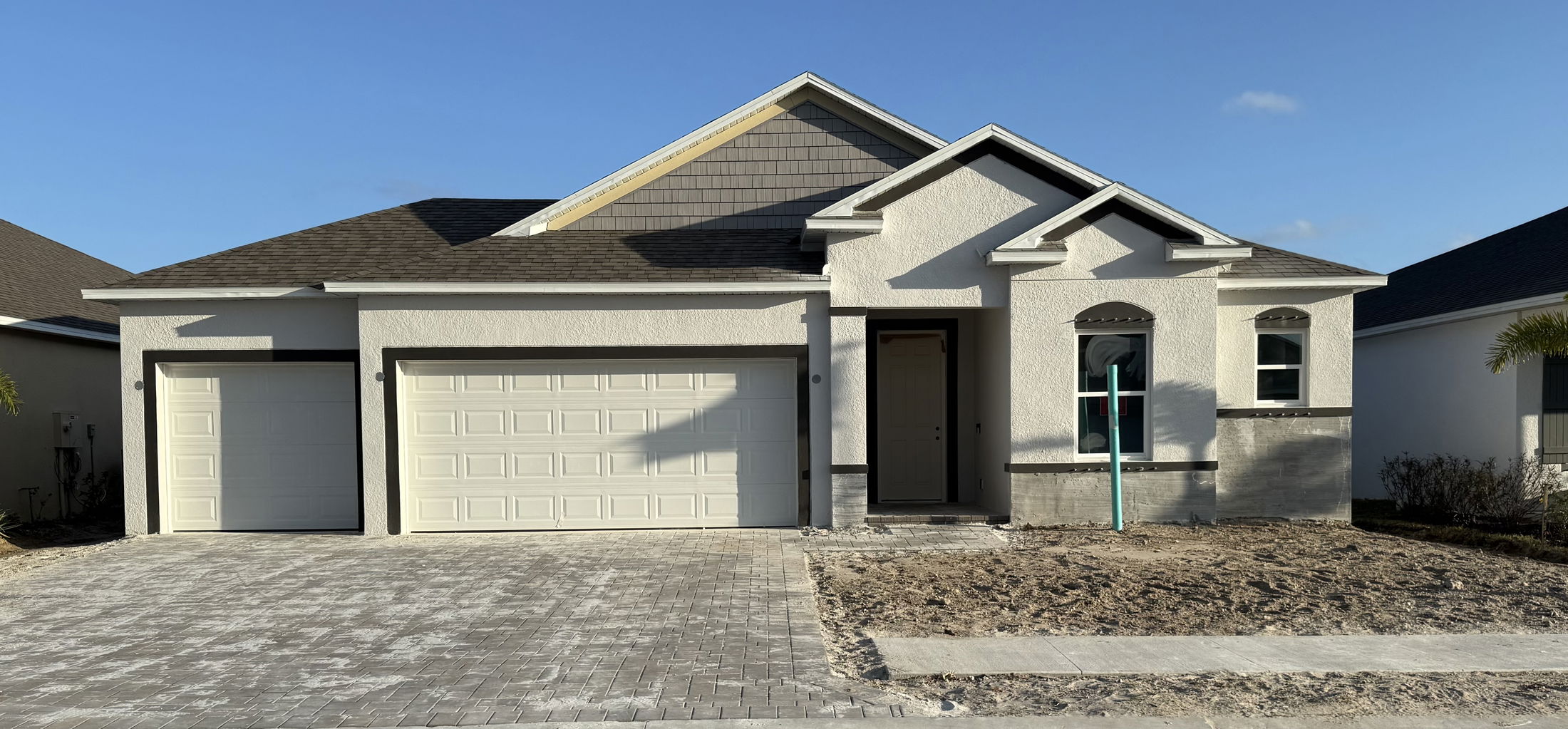 Newly constructed single-story modern house with a spacious driveway and three-car garage.